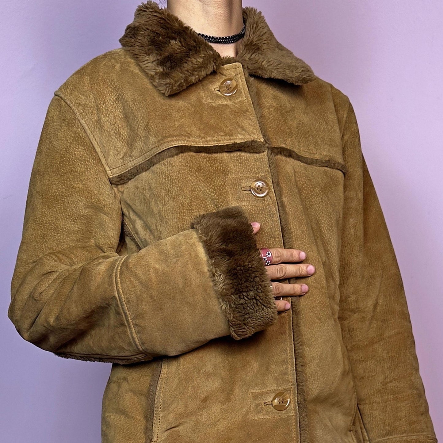 The Vintage 90s Brown Shearling Leather Jacket is crafted from genuine leather with a plush shearling interior for exceptional warmth and comfort. Featuring button closures, fur-lined cuffs, and a cozy collar
