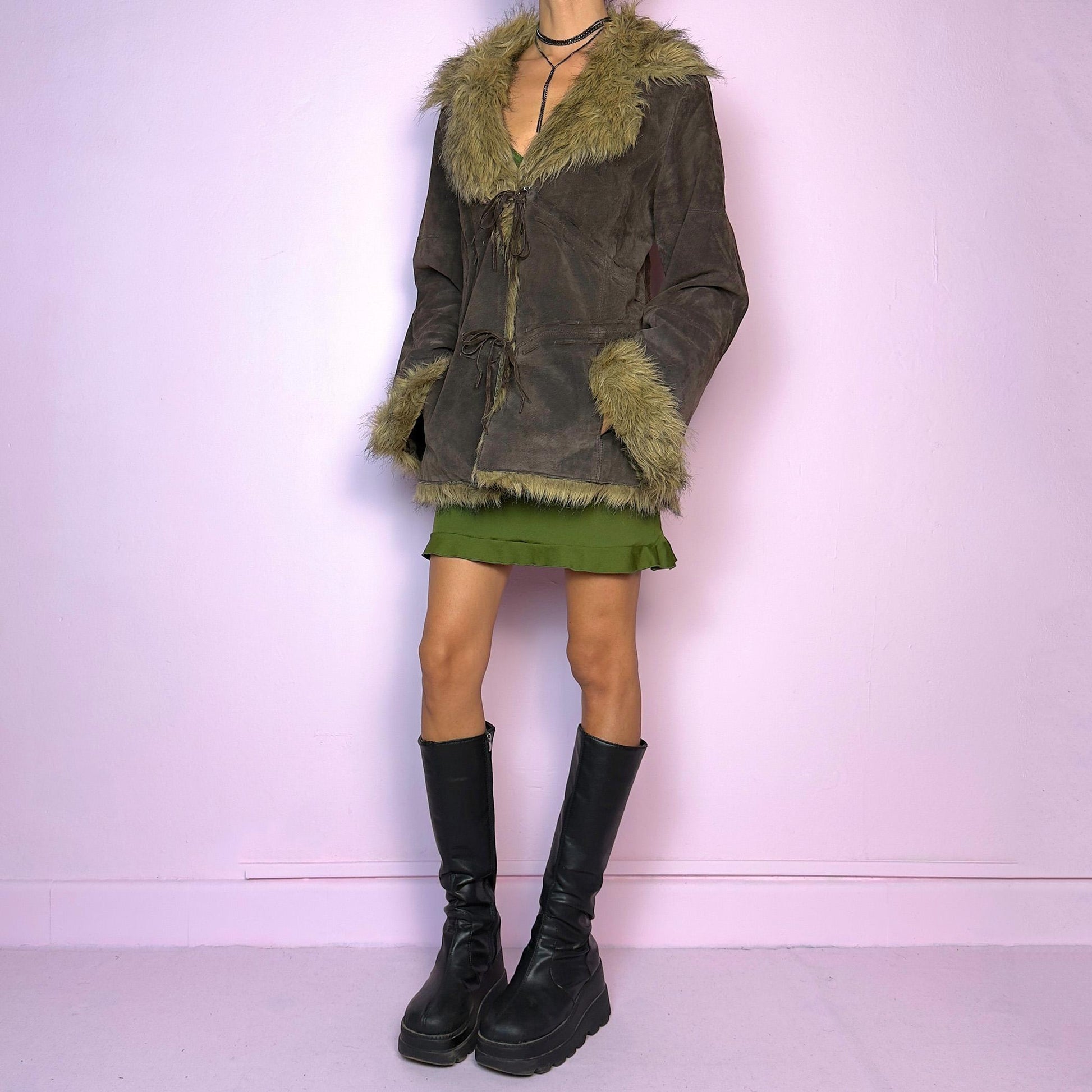 The Vintage 90s Brown Suede Penny Lane Jacket features a brown leather suede exterior and plush faux fur trim on the collar, cuffs, and hemline. Featuring tie-front closures for a snug fit and a flattering silhouette