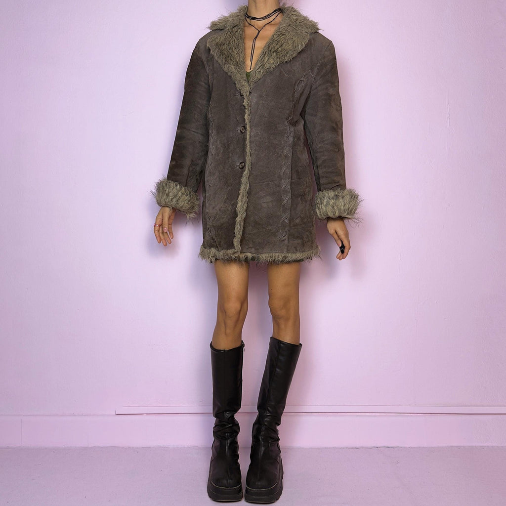 The Vintage 90s Brown Suede Penny Lane Coat showcases a brown leather suede finish paired with soft faux fur trims along the collar, cuffs, and hemline. This jacket features button closures and intricate stitch details. Its timeless design
