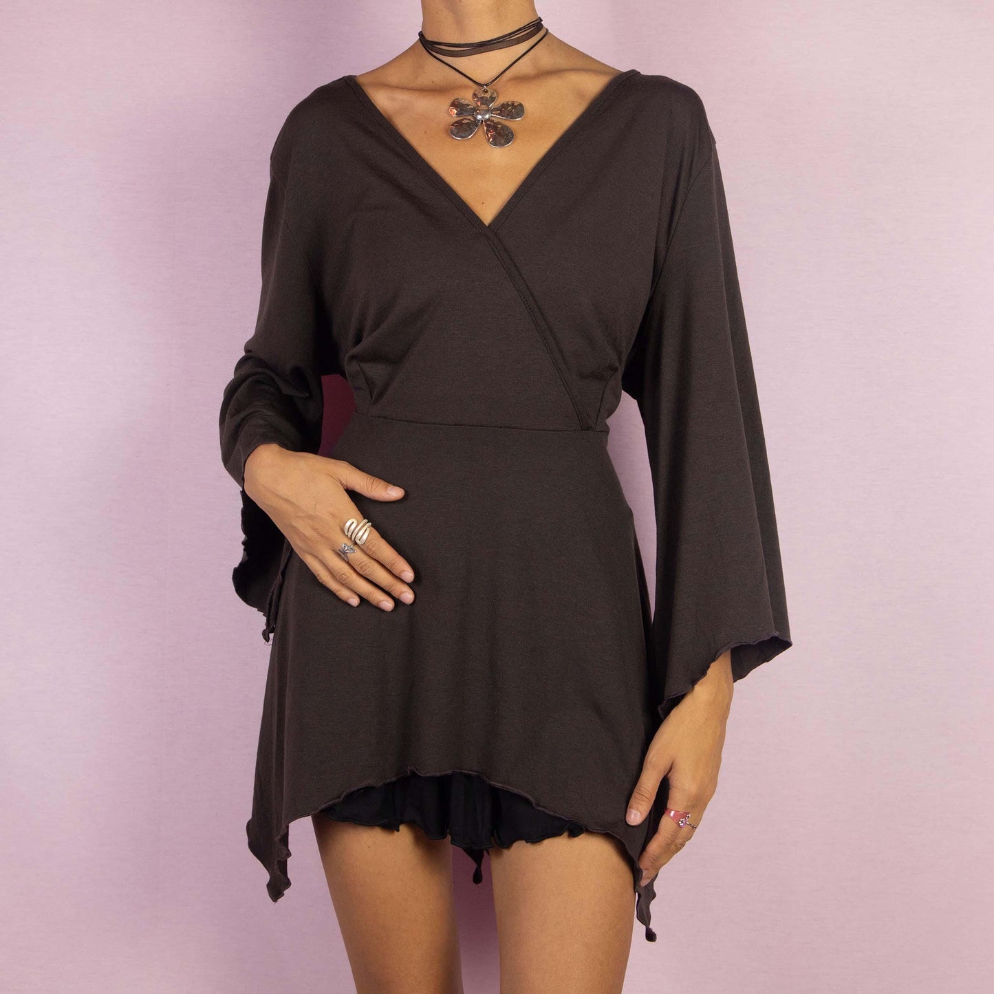 The Y2K Brown Bell Sleeve Top is a whimsical vintage 2000s blouse featuring a deep V-neckline and dramatic bell sleeves that enhance its enchanting boho-inspired aesthetic. The asymmetrical hem adds a unique, flowy silhouette.