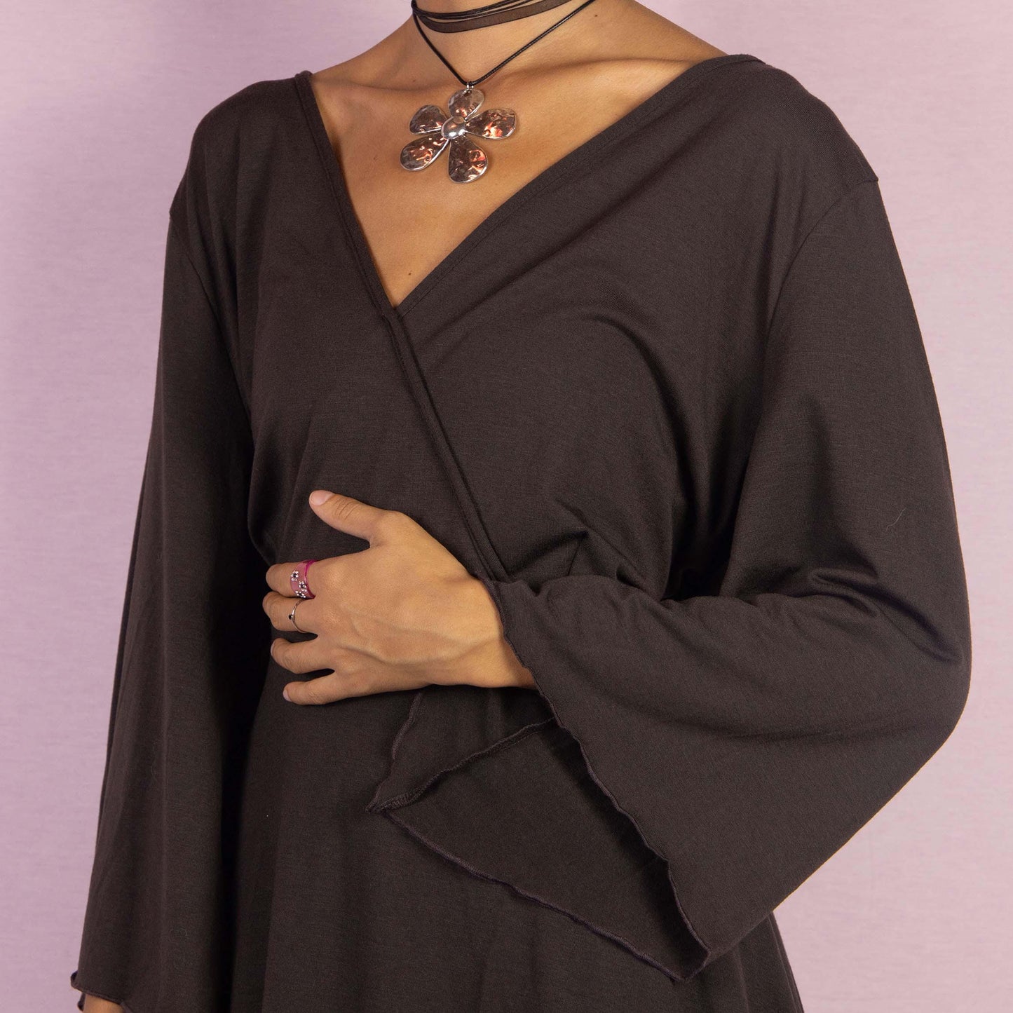 The Y2K Brown Bell Sleeve Top is a whimsical vintage 2000s blouse featuring a deep V-neckline and dramatic bell sleeves that enhance its enchanting boho-inspired aesthetic. The asymmetrical hem adds a unique, flowy silhouette.