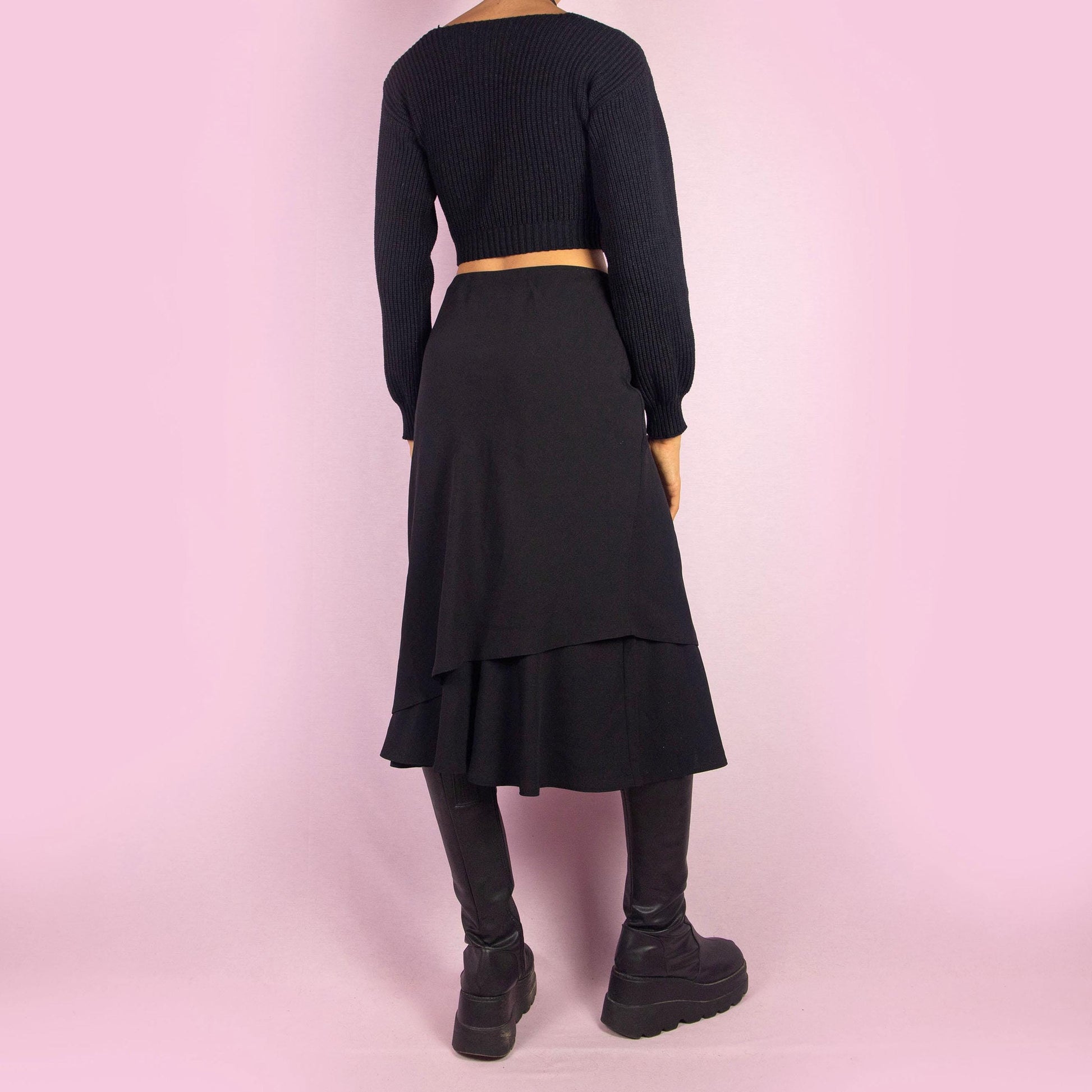 The Vintage 90s Black Layered Midi Skirt showcases a layered design with a flared underlayer peeking out for an elegant silhouette. Featuring an elastic waist, this midi-length skirt is perfect for both office wear and evening occasions.