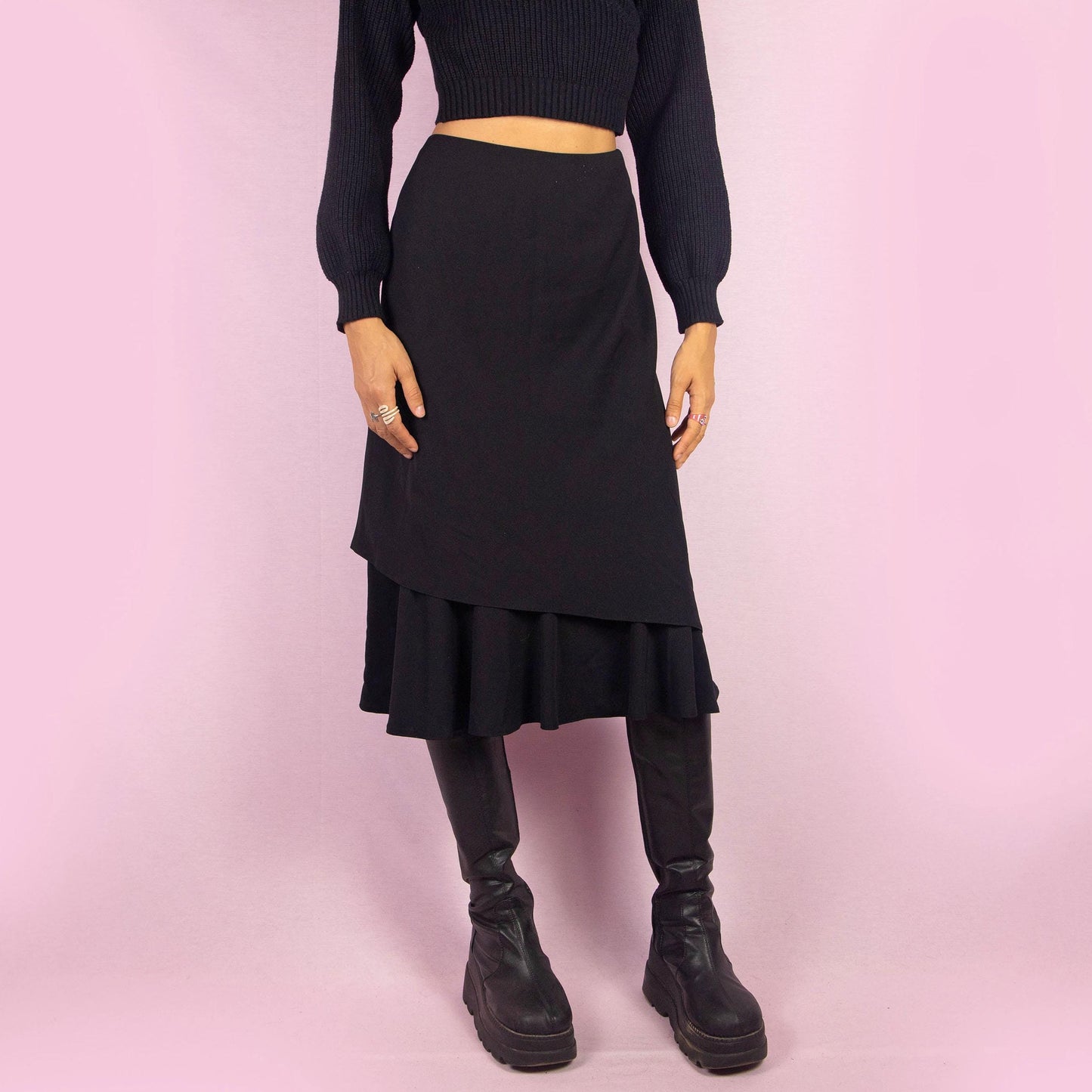 The Vintage 90s Black Layered Midi Skirt showcases a layered design with a flared underlayer peeking out for an elegant silhouette. Featuring an elastic waist, this midi-length skirt is perfect for both office wear and evening occasions.
