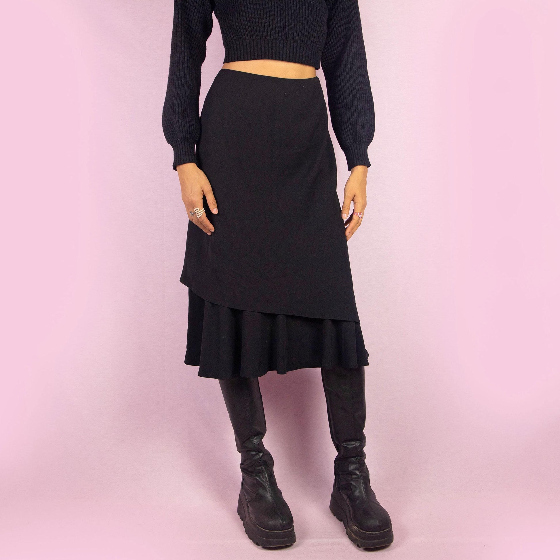 The Vintage 90s Black Layered Midi Skirt showcases a layered design with a flared underlayer peeking out for an elegant silhouette. Featuring an elastic waist, this midi-length skirt is perfect for both office wear and evening occasions.
