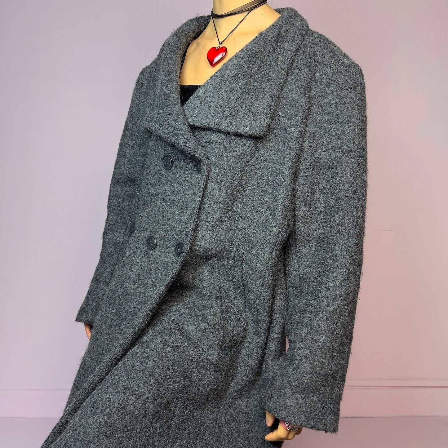 The Y2K Gray Wool Coat is a vintage 2000s timeless piece crafted from a soft and warm wool and polyester blend. It features a double-breasted front with oversized buttons, a wide lapel collar, and side pockets for a cozy design. Its relaxed fit