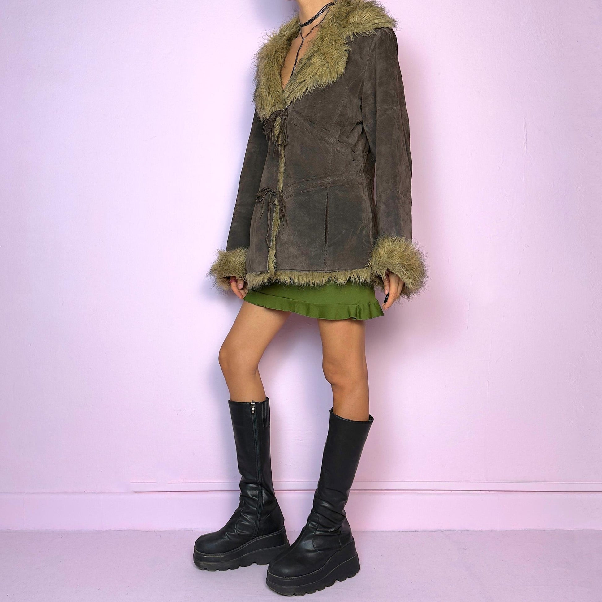 The Vintage 90s Brown Suede Penny Lane Jacket features a brown leather suede exterior and plush faux fur trim on the collar, cuffs, and hemline. Featuring tie-front closures for a snug fit and a flattering silhouette