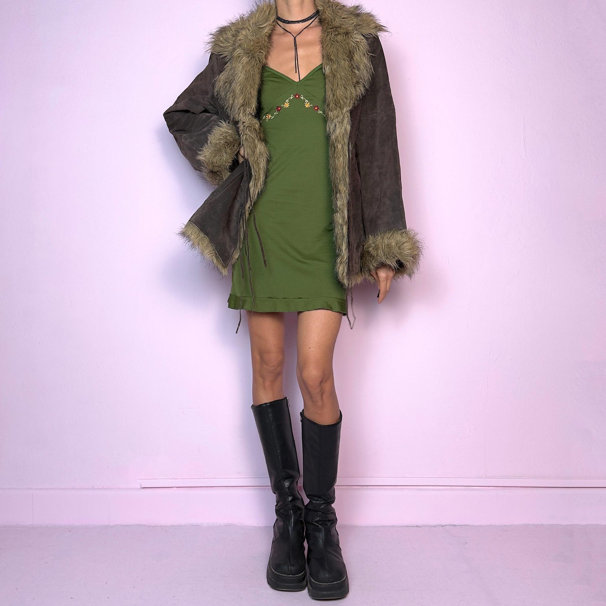 The Vintage 90s Brown Suede Penny Lane Jacket features a brown leather suede exterior and plush faux fur trim on the collar, cuffs, and hemline. Featuring tie-front closures for a snug fit and a flattering silhouette