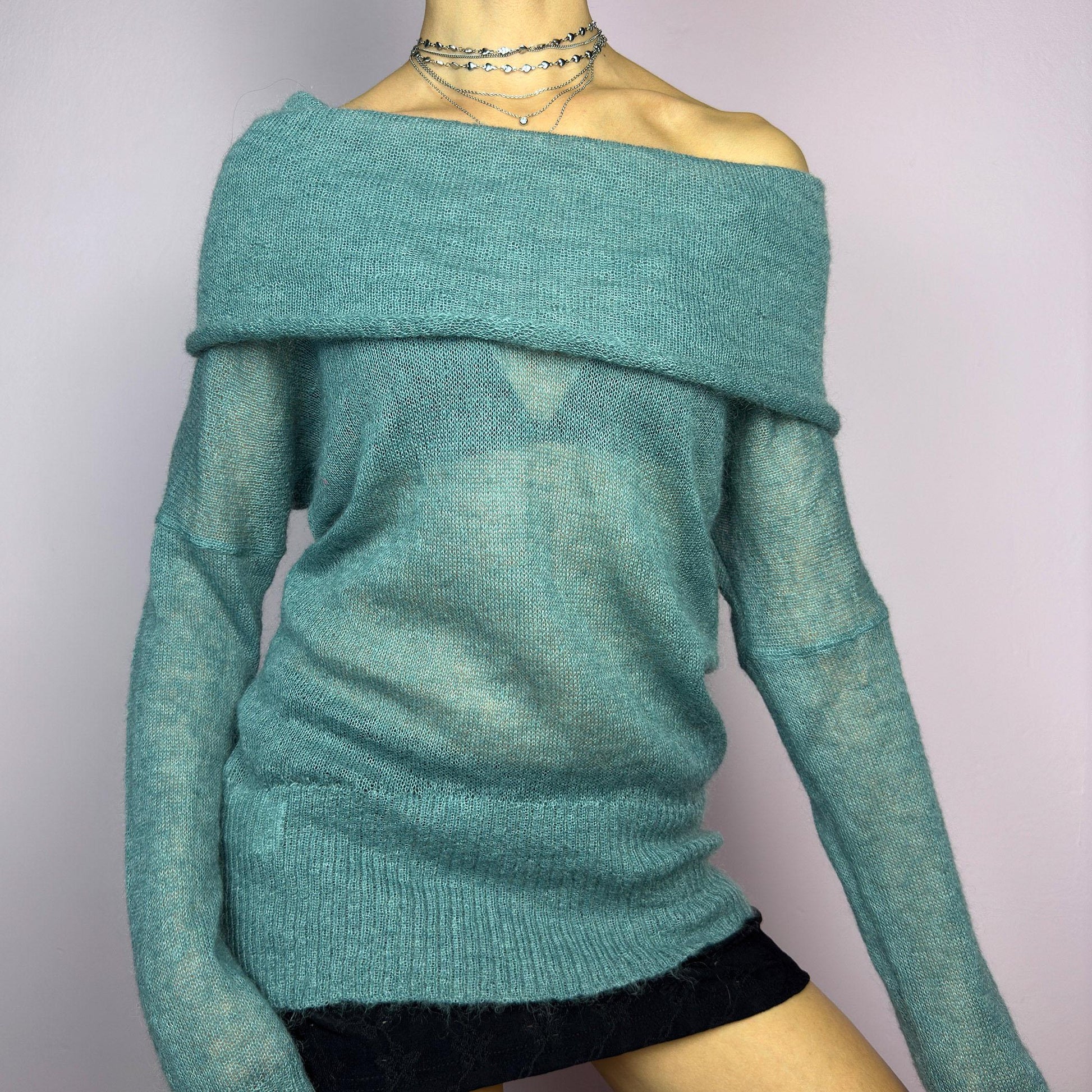 The Y2K Blue Off-Shoulder Sweater is a vintage 2000s cozy and comfy piece made from a mohair, wool, and nylon blend. This soft, semi-sheer sweater features a folded off-shoulder neckline and a muted blue hue. adult world shop