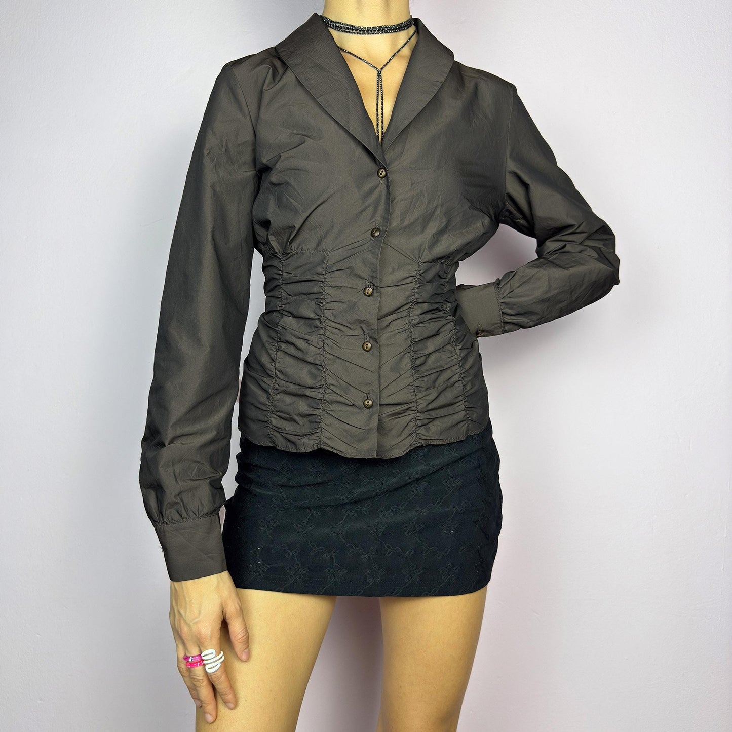 The Vintage 90s Brown Ruched Blouse features a structured yet feminine design with ruched detailing on both the front and back, creating a flattering silhouette. Crafted in a deep brown tone, it includes a tailored collar. adult world shop