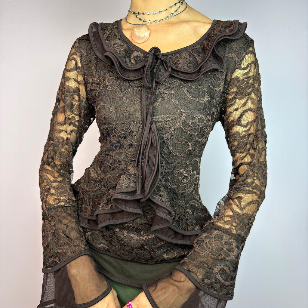 The Y2K Brown Lace Ruffle Top is a vintage 2000s statement piece, showcasing intricate floral lace throughout for a romantic and feminine look. This top features a stretchy semi-sheer fabric, layered ruffles along the neckline. adult world shop