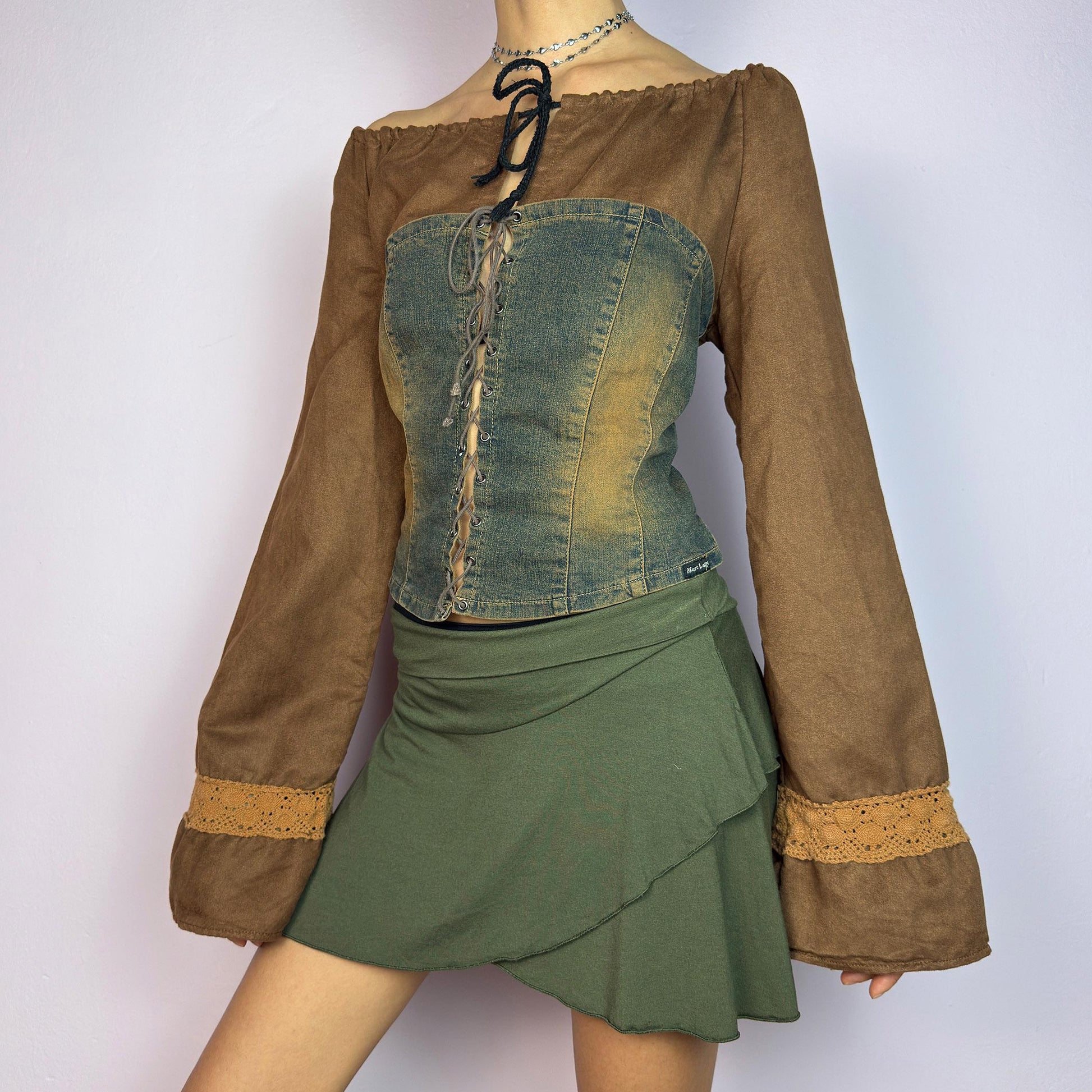 The Y2K Brown Denim Corset Top is a vintage 2000s statement piece blending earthy tones. Crafted with faux suede, this off-the-shoulder top features flared bell long sleeves adorned with crochet lace accents. adult world shop