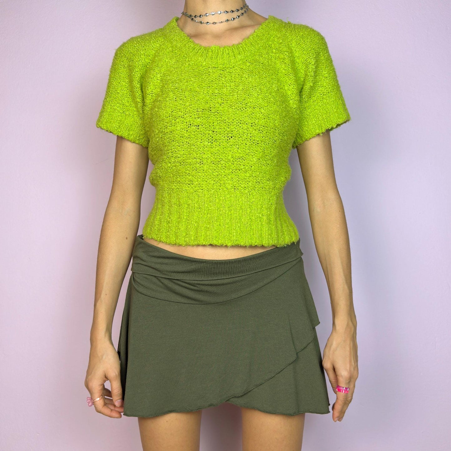 The Y2K Green Knitted Top is a vibrant vintage 2000s piece featuring a lime-green hue. Designed with a cropped silhouette, short sleeves, and a stretchy ribbed hem, this knit top adds a playful touch to casual outfits. adult world shop