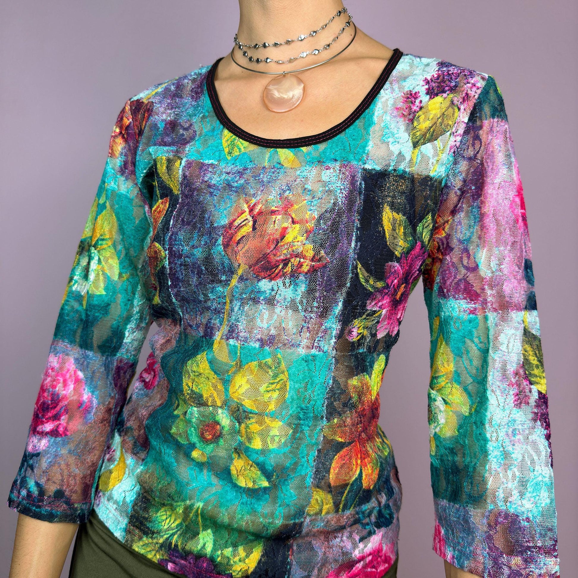 The Y2K Painting Lace Mesh Top is a vintage 2000s artistic statement piece. Featuring a semi-sheer lace fabric adorned with a bold, vibrant floral pattern resembling a painterly masterpiece, a scoop neckline and 3/4 sleeves. adult world shop