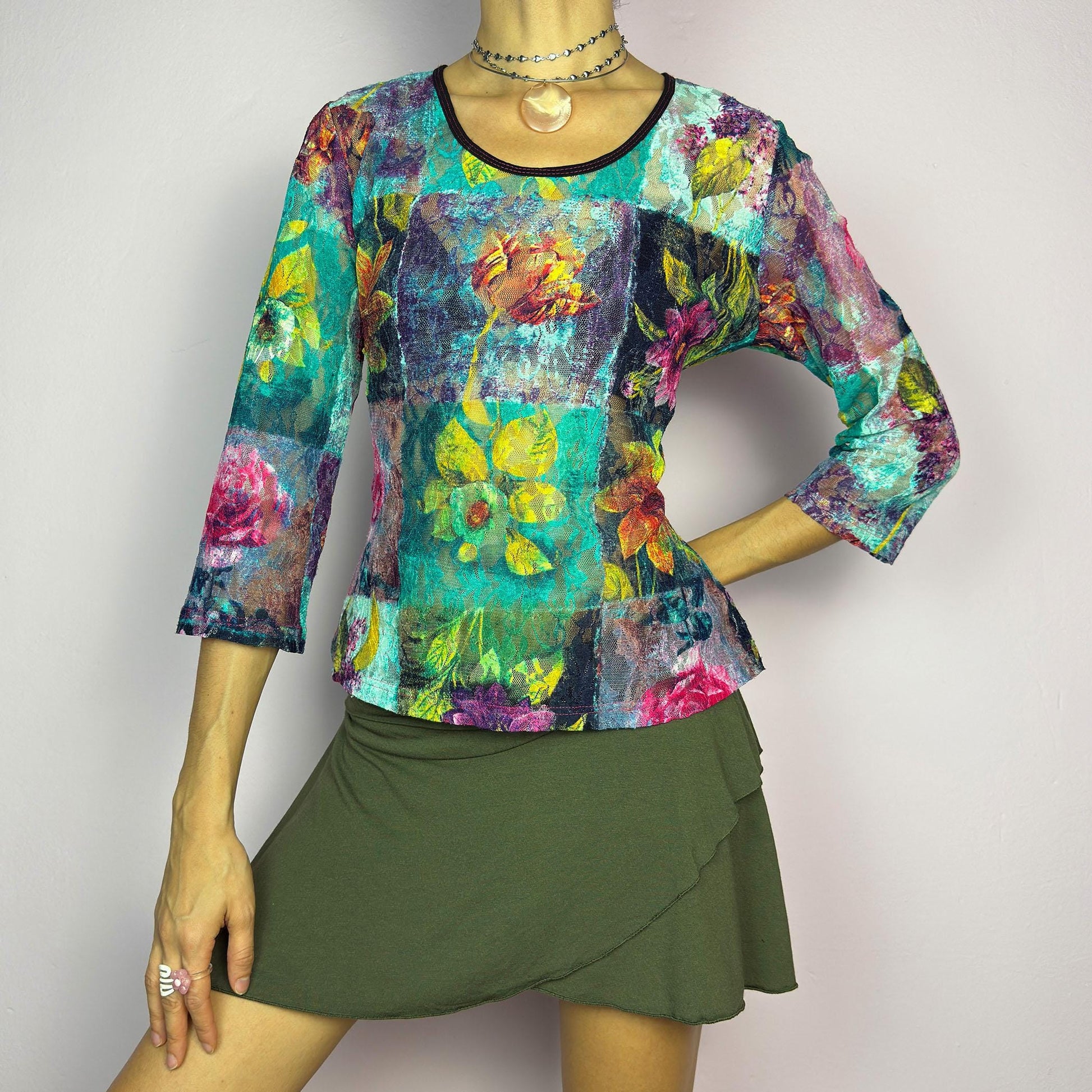 The Y2K Painting Lace Mesh Top is a vintage 2000s artistic statement piece. Featuring a semi-sheer lace fabric adorned with a bold, vibrant floral pattern resembling a painterly masterpiece, a scoop neckline and 3/4 sleeves. adult world shop