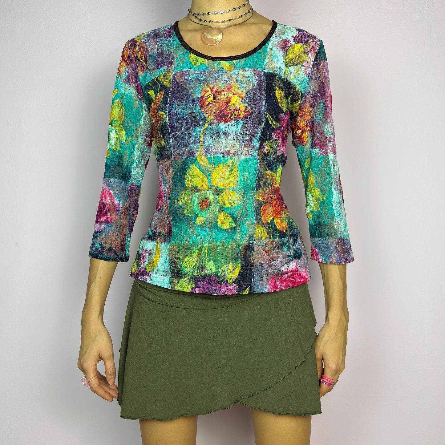 The Y2K Painting Lace Mesh Top is a vintage 2000s artistic statement piece. Featuring a semi-sheer lace fabric adorned with a bold, vibrant floral pattern resembling a painterly masterpiece, a scoop neckline and 3/4 sleeves. adult world shop