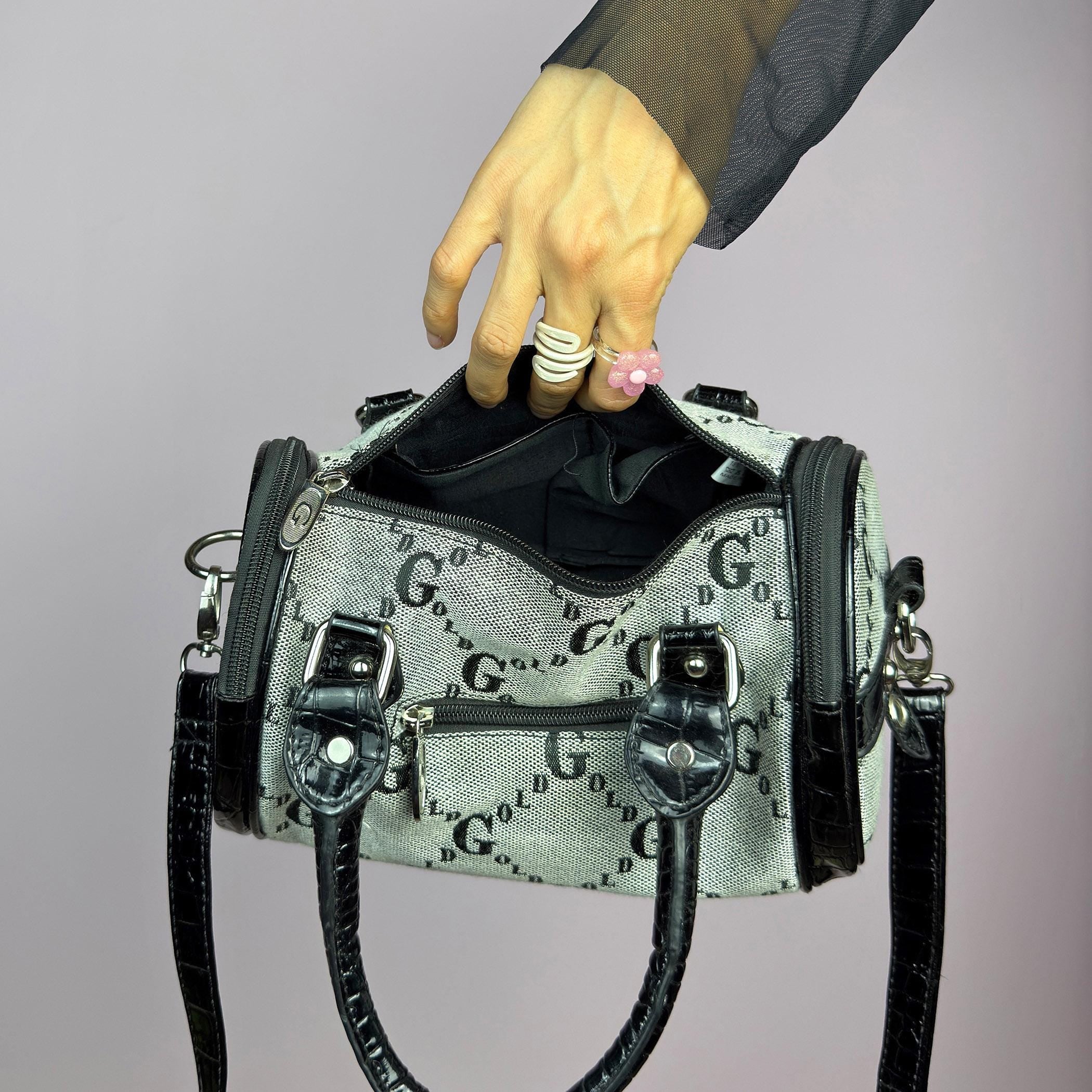 The Y2K Monogram Mini Duffel Bag is a stylish vintage 2000s accessory. Featuring a structured silhouette with an all-over monogram print, sleek black faux patent leather accents, and silver hardware. It includes dual top handles. adult world shop