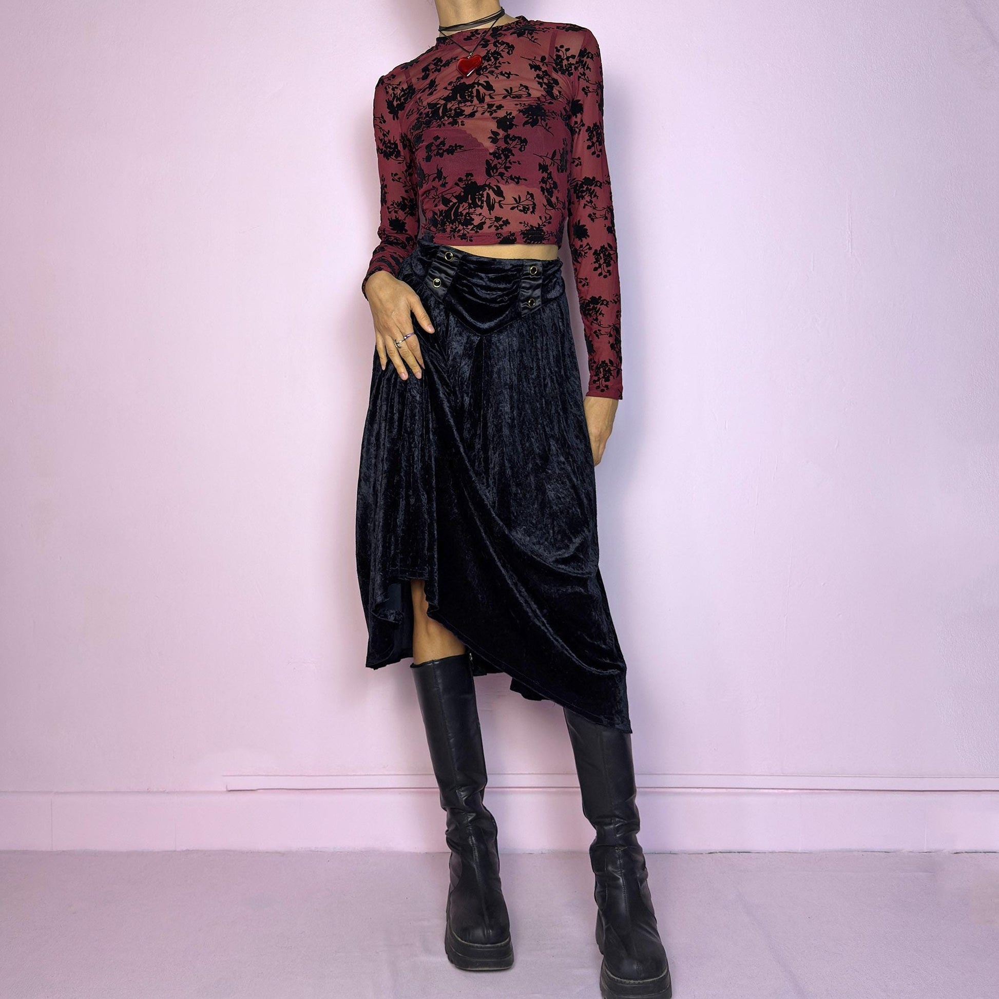 The Vintage 90s Black Velvet Midi Skirt is crafted from soft velvet and features an elastic waistband detail with button accents and a flowing A-line silhouette. Ideal for night parties and embodies a whimsical goth aesthetic. Adult World Shop