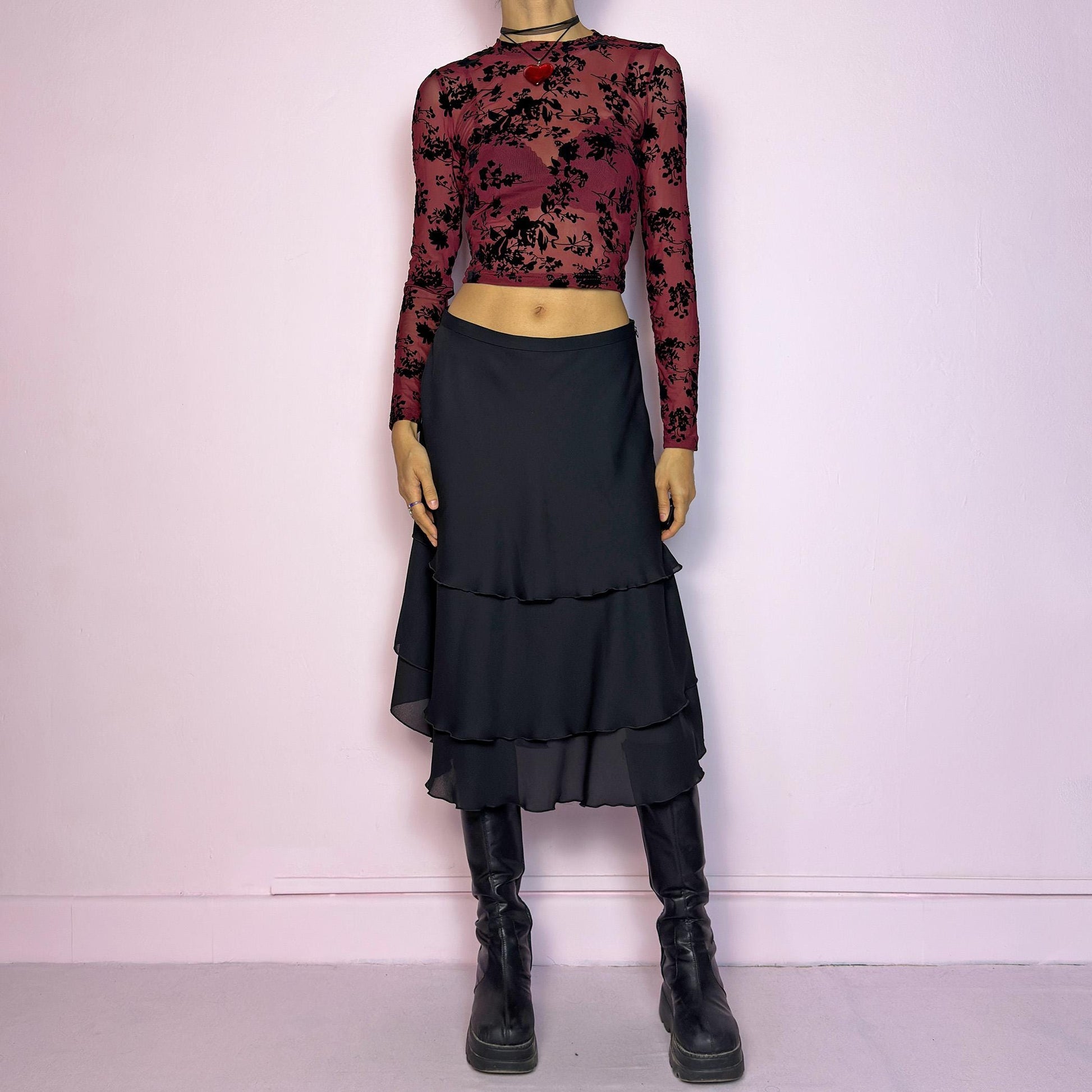 The Vintage 90s Black Layered Tiered Skirt features a flowy, tiered design with cascading chiffon-like layers. It includes a side zipper closure. Its versatile length and elegant style make it perfect for evening parties. Adult World Shop