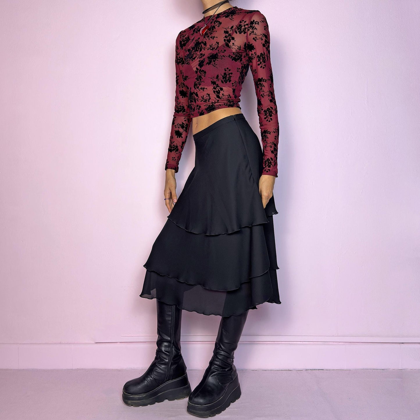 The Vintage 90s Black Layered Tiered Skirt features a flowy, tiered design with cascading chiffon-like layers. It includes a side zipper closure. Its versatile length and elegant style make it perfect for evening parties. Adult World Shop