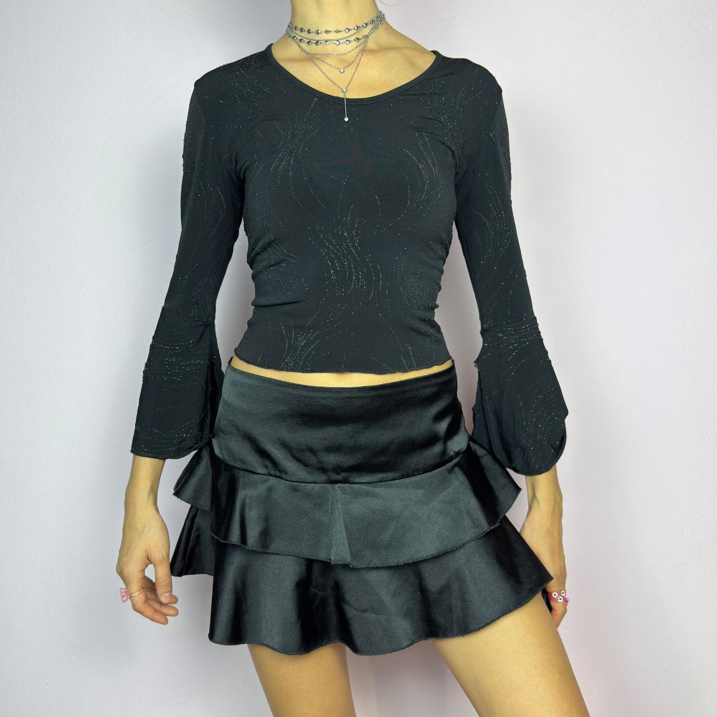 The Y2K Black Ruffle Satin Mini Skirt is a vintage 2000s piece made from a sleek satin-style stretchy fabric featuring layered ruffles, low rise design and a side zipper closure. Ideal for a night-out outfit. adult world shop
