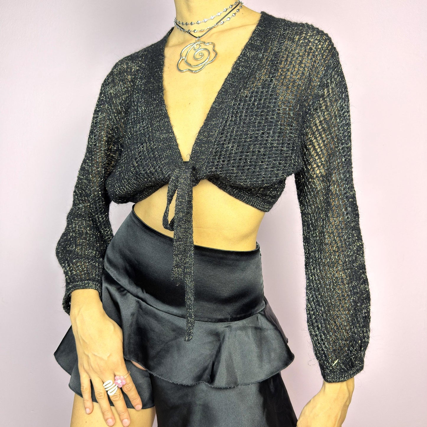 This Y2K Black Tie Front Cardigan is a vintage 2000s piece featuring a lightweight open-knit design with a subtle metallic shimmer, a cropped fit and long sleeves. Perfect for layering and ideal for night-out or casual outfits.