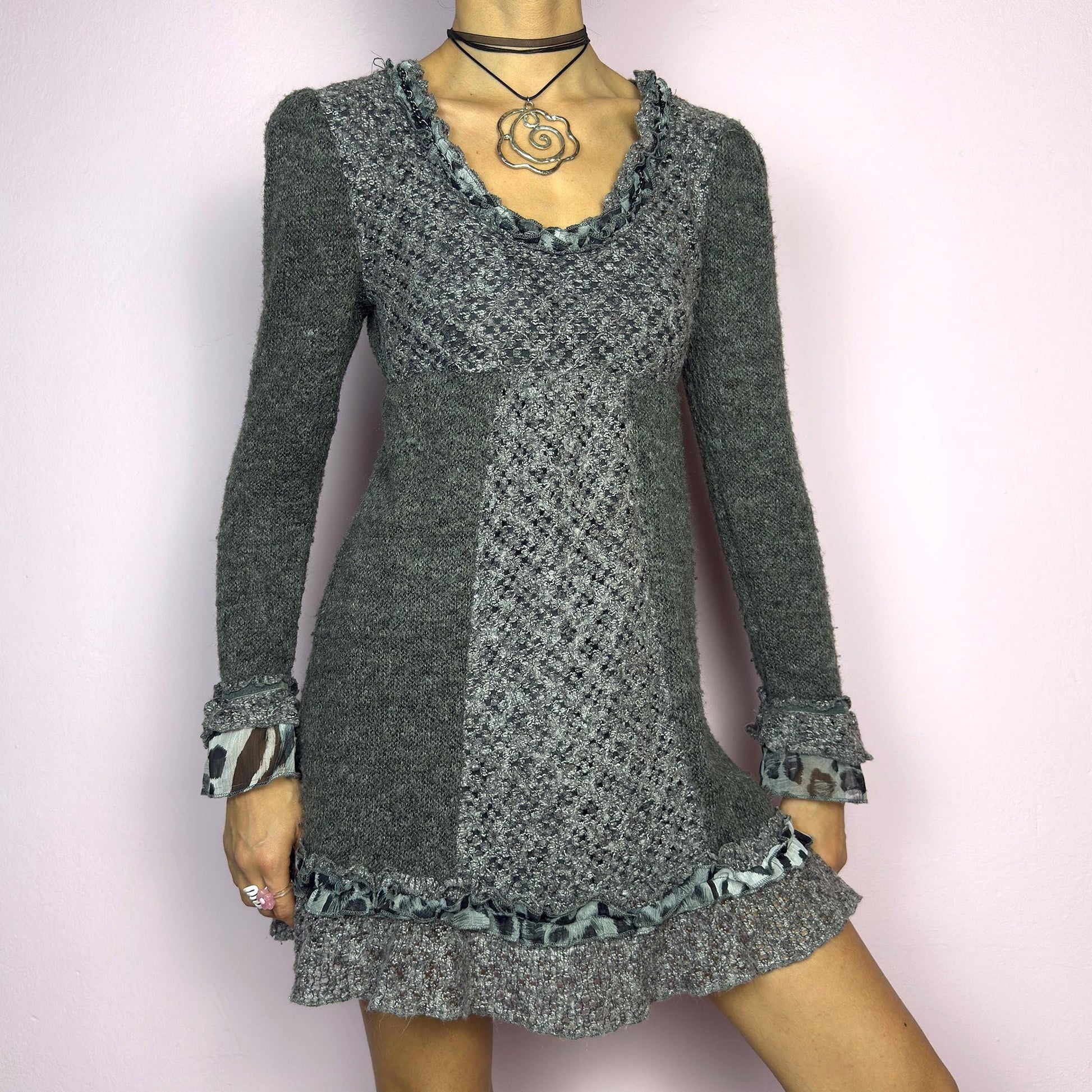 The Y2K Gray Knit Mini Dress is a vintage 2000s piece featuring a patchwork knit design with ruffle trim details. With a fitted bust and flared hem, this dress has a romantic and whimsical aesthetic. The long sleeves add a cozy. adult world shop
