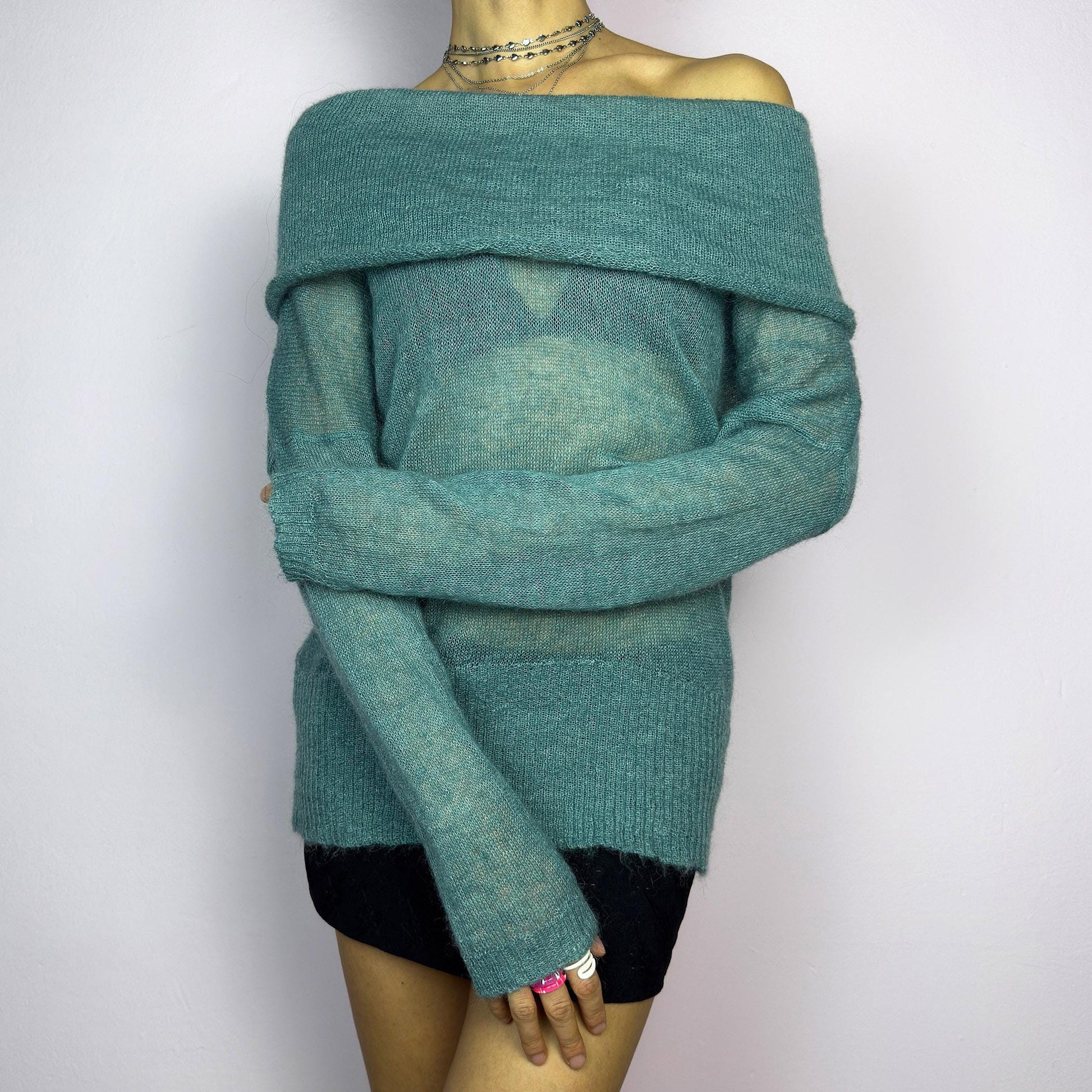 The Y2K Blue Off-Shoulder Sweater is a vintage 2000s cozy and comfy piece made from a mohair, wool, and nylon blend. This soft, semi-sheer sweater features a folded off-shoulder neckline and a muted blue hue. adult world shop