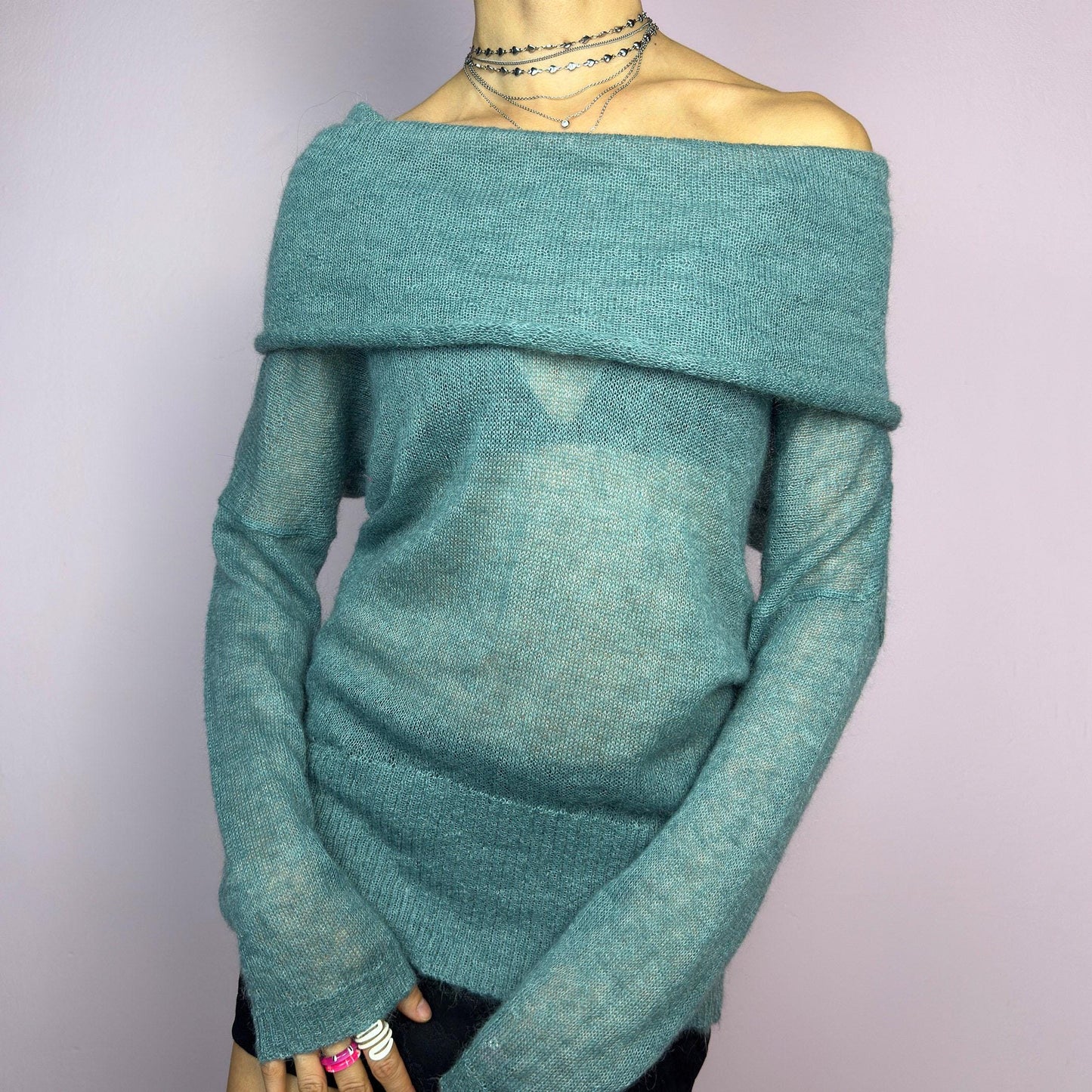 The Y2K Blue Off-Shoulder Sweater is a vintage 2000s cozy and comfy piece made from a mohair, wool, and nylon blend. This soft, semi-sheer sweater features a folded off-shoulder neckline and a muted blue hue. adult world shop