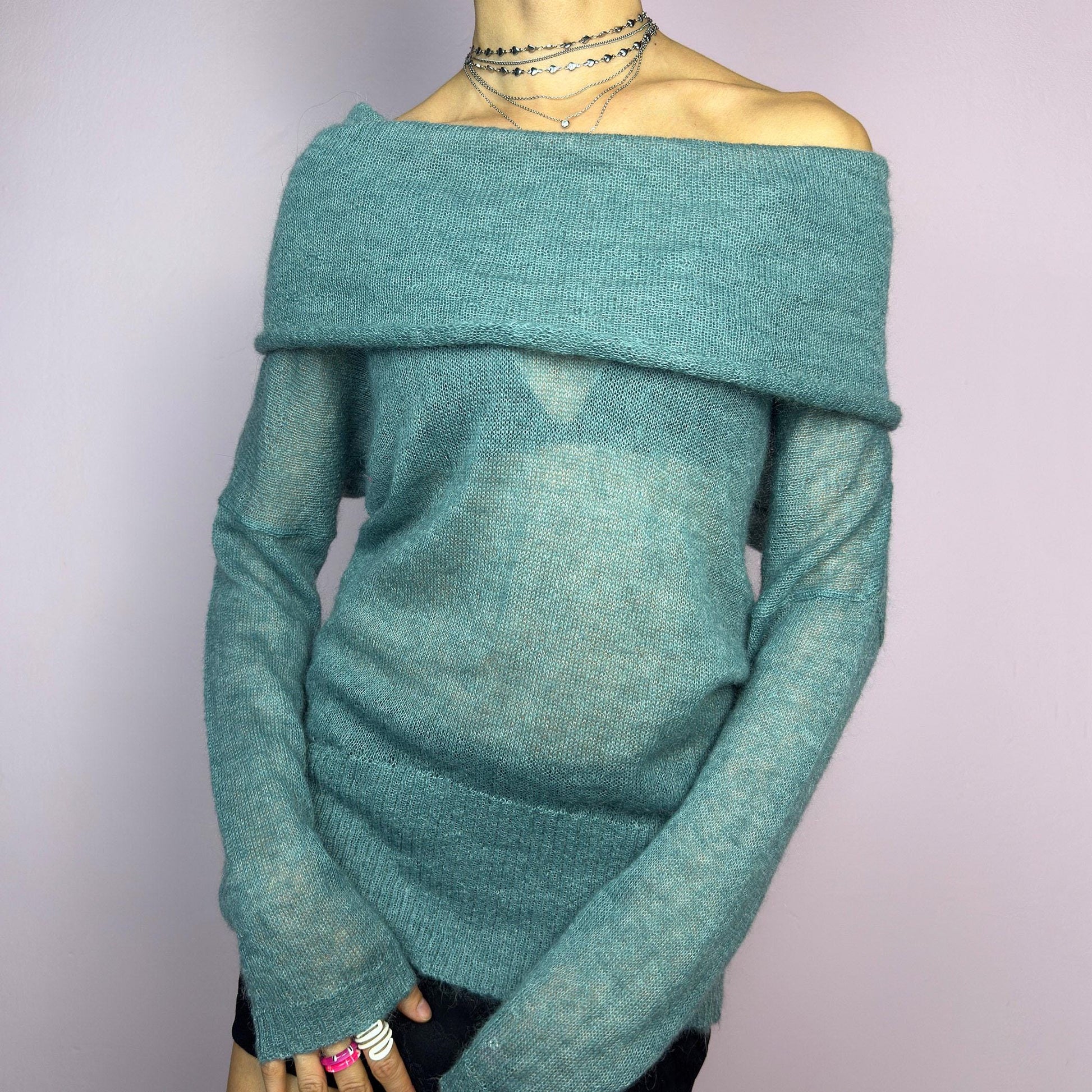 The Y2K Blue Off-Shoulder Sweater is a vintage 2000s cozy and comfy piece made from a mohair, wool, and nylon blend. This soft, semi-sheer sweater features a folded off-shoulder neckline and a muted blue hue. adult world shop