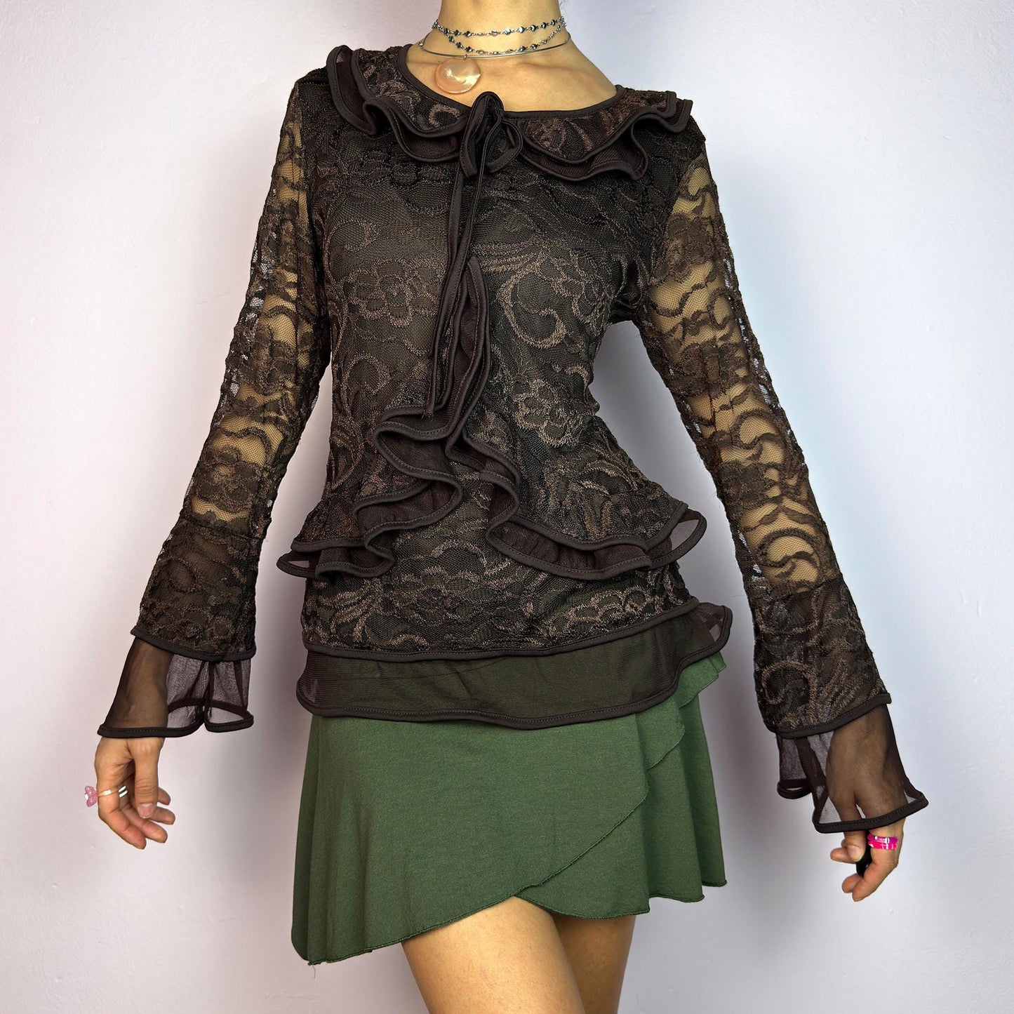 The Y2K Brown Lace Ruffle Top is a vintage 2000s statement piece, showcasing intricate floral lace throughout for a romantic and feminine look. This top features a stretchy semi-sheer fabric, layered ruffles along the neckline. adult world shop