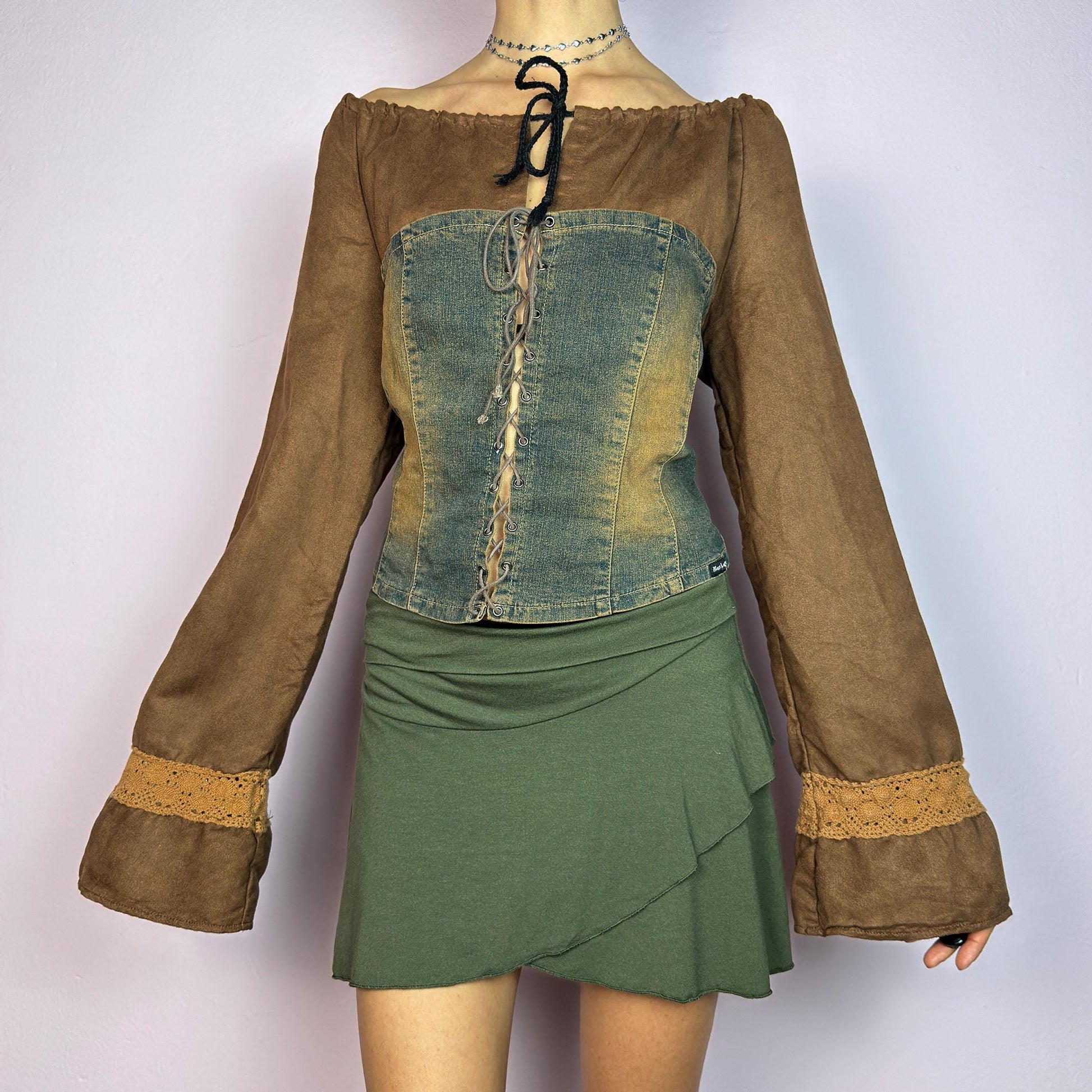 The Y2K Brown Denim Corset Top is a vintage 2000s statement piece blending earthy tones. Crafted with faux suede, this off-the-shoulder top features flared bell long sleeves adorned with crochet lace accents. adult world shop