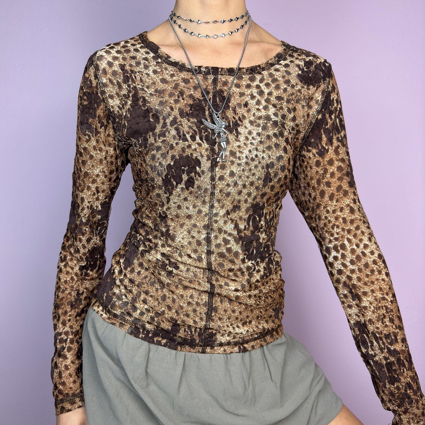 The Y2K Animal Print Mesh Top is a vintage 2000s sheer long-sleeve top featuring a bold cheetah-inspired print in earthy brown tones. Designed with visible contrast stitching, and a soft stretch mesh fabric, this piece is perfect for casual or night-out looks. adult world shop
