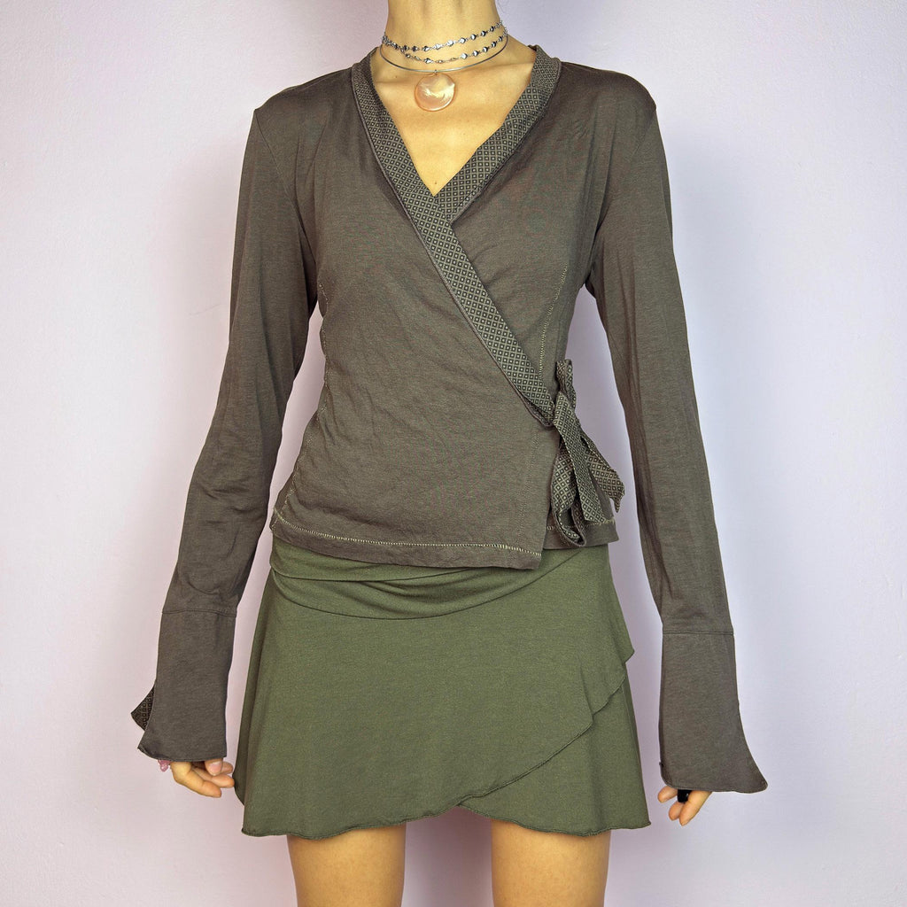 The Y2K Brown Wrap Cop Copine Top is a sleek and minimalist 2000s piece featuring a wrap-tie design with geometric-patterned trim details and flared cuffs. This top is crafted from a stretchy, comfortable fabric. adult world shop