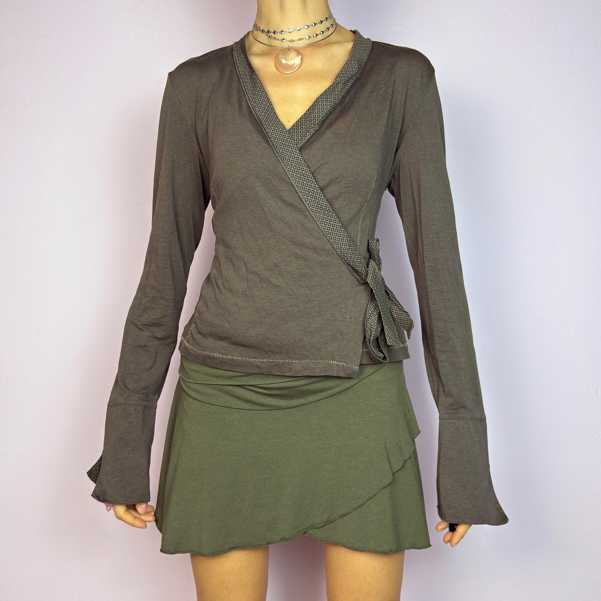 The Y2K Brown Wrap Cop Copine Top is a sleek and minimalist 2000s piece featuring a wrap-tie design with geometric-patterned trim details and flared cuffs. This top is crafted from a stretchy, comfortable fabric. adult world shop