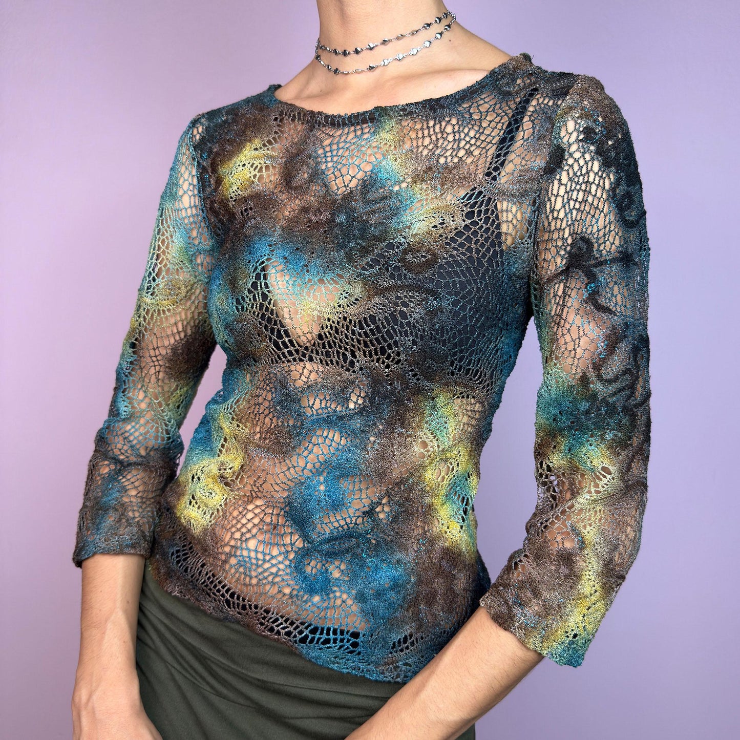 The Y2K Open Knit Mesh Top is a unique vintage 2000s piece featuring an intricate open-knit design, this semi-sheer top boasts a dreamy tie-dye-inspired blend of earthy hues in brown, blue and green. adult world shop