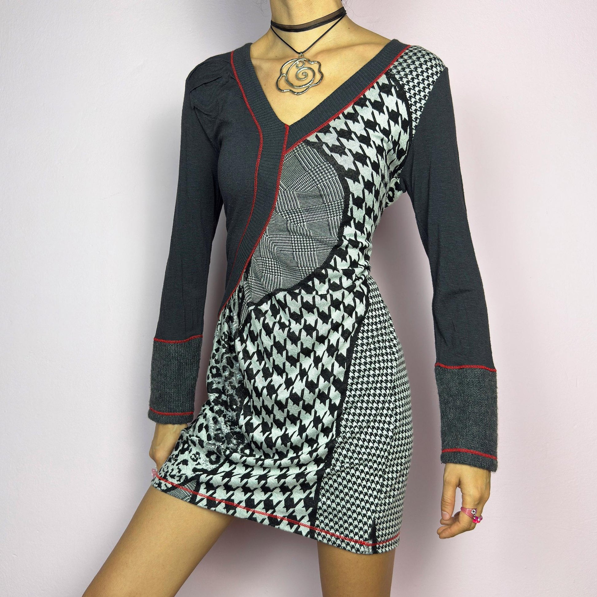 The Y2K Gray Patchwork Mini Dress is a vintage 2000s piece featuring a bold patchwork print with a mix of houndstooth, plaid, and leopard patterns, a V-neckline and long sleeves. The fitted silhouette. adult world shop