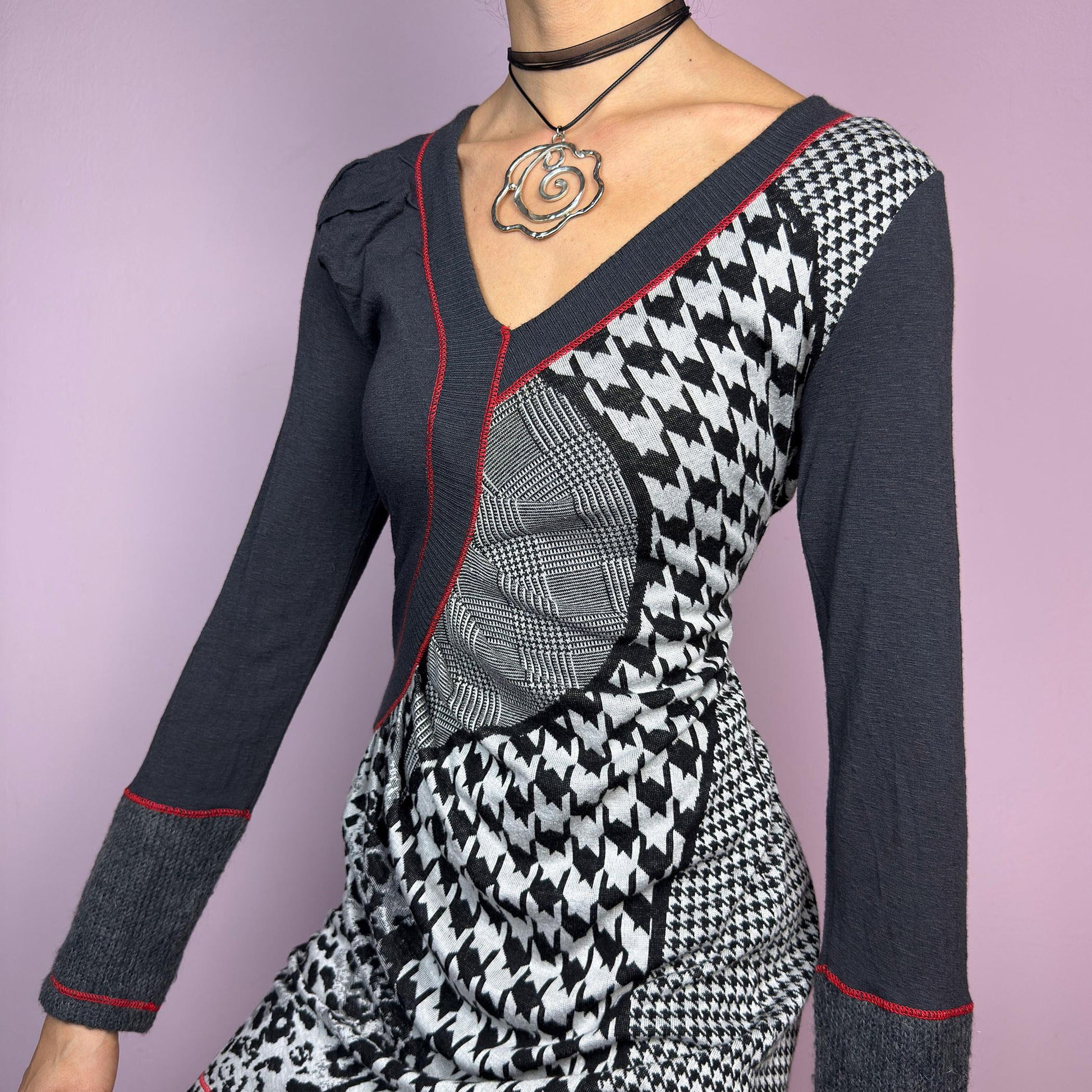 The Y2K Gray Patchwork Mini Dress is a vintage 2000s piece featuring a bold patchwork print with a mix of houndstooth, plaid, and leopard patterns, a V-neckline and long sleeves. The fitted silhouette. adult world shop
