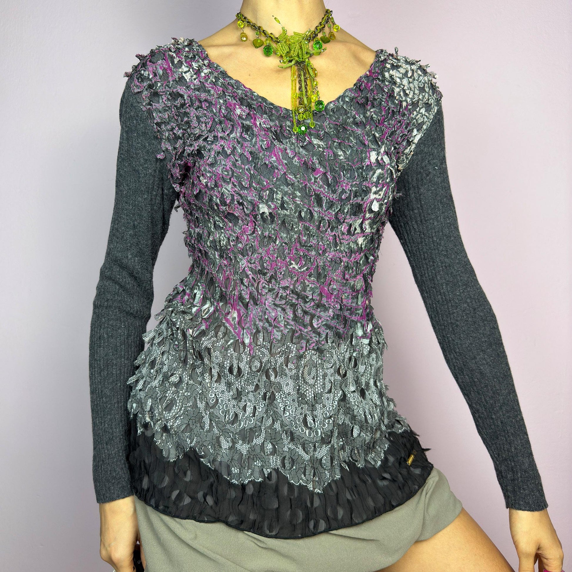 The Y2K Gray Crinkled Textured Top is a vintage 2000s piece by designer Roberto Verino, featuring a unique sheer overlay with delicate cut-out details that create a dimensional, deconstructed look. The long knit sleeves contrast beautifully with the intricate textures, adding depth to this stretchy fit design. A standout piece for those who love avant-garde fashion. adult world shop