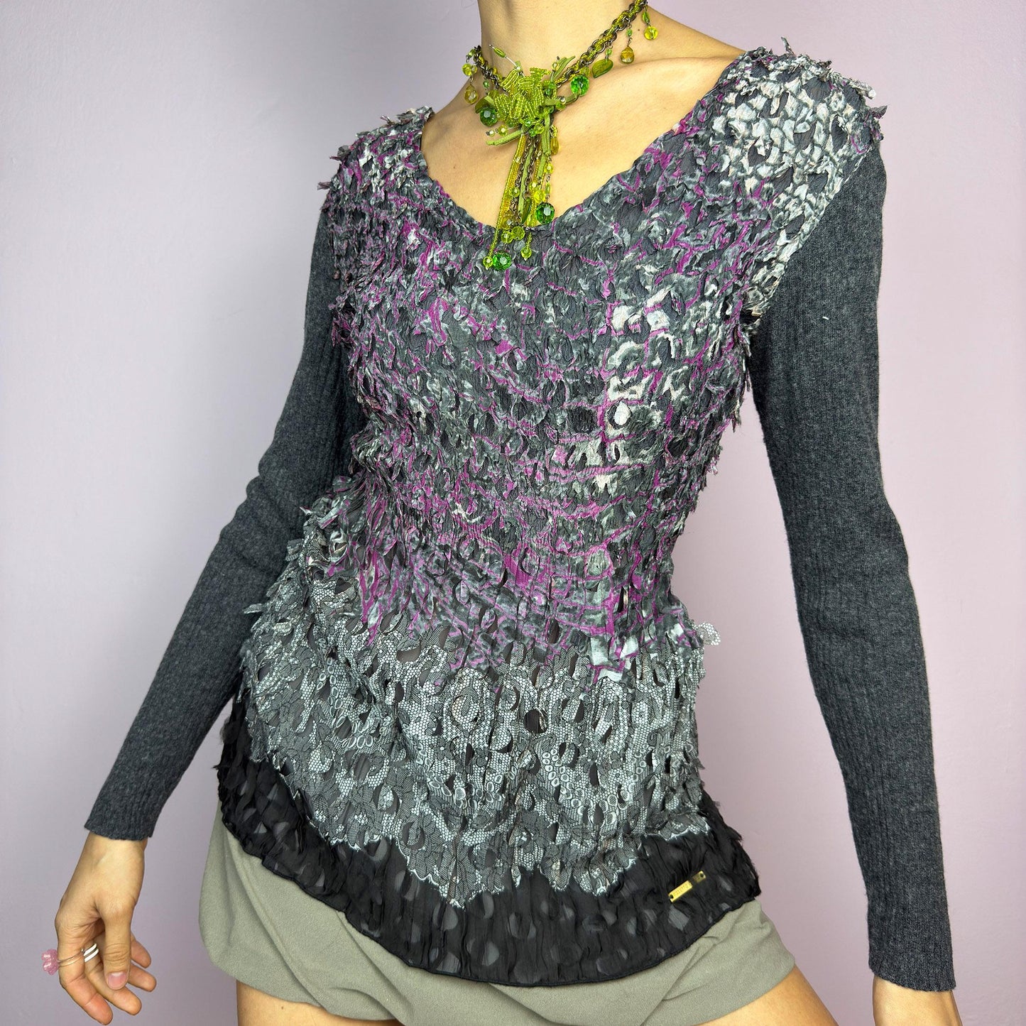The Y2K Gray Crinkled Textured Top is a vintage 2000s piece by designer Roberto Verino, featuring a unique sheer overlay with delicate cut-out details that create a dimensional, deconstructed look. The long knit sleeves contrast beautifully with the intricate textures, adding depth to this stretchy fit design. A standout piece for those who love avant-garde fashion. adult world shop