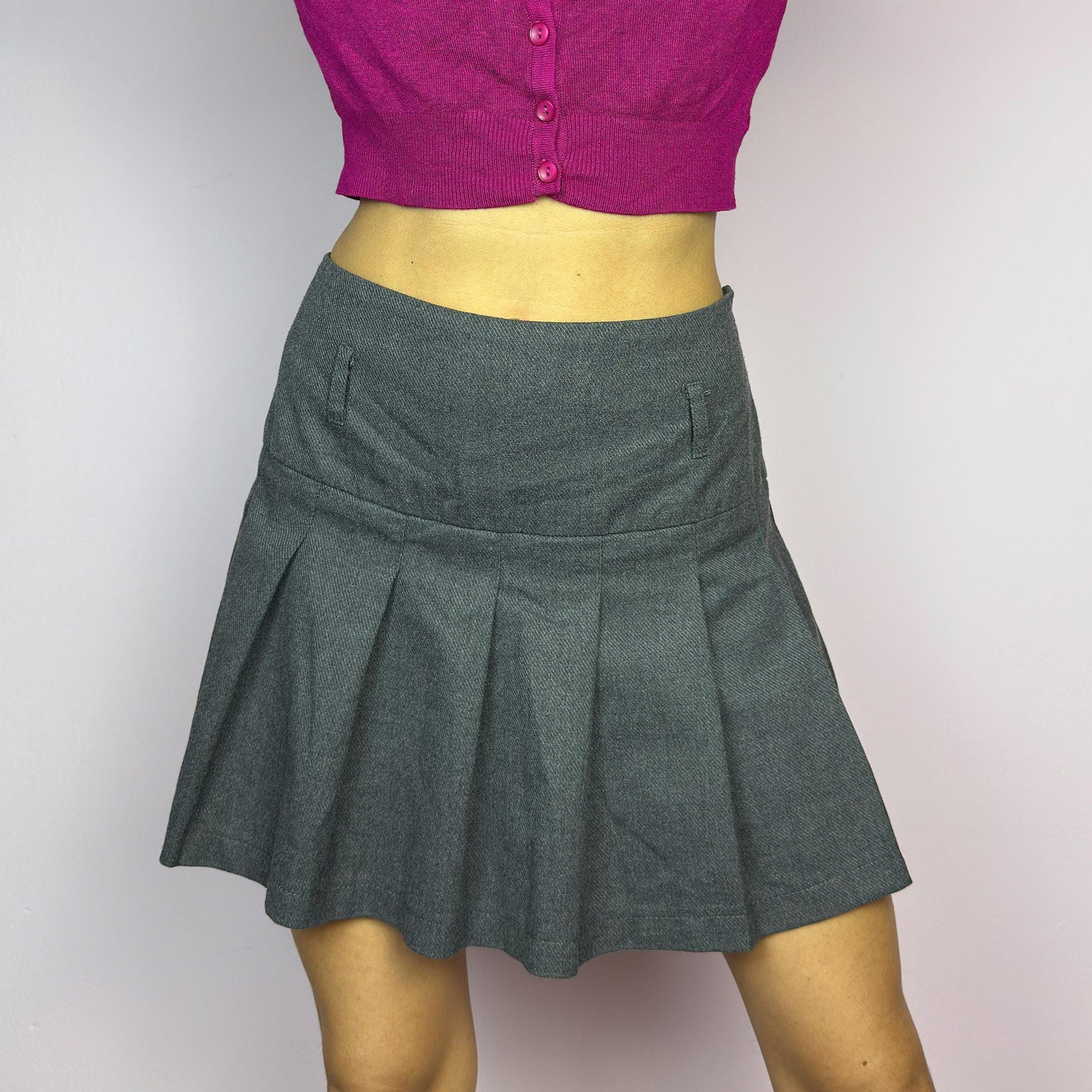 The Y2K Gray Pleated Mini Skirt is a vintage 2000s essential, featuring a structured pleated design and a side zipper closure. Made from a thick woven fabric, is perfect for preppy, grunge, or casual outfits. adult world shop