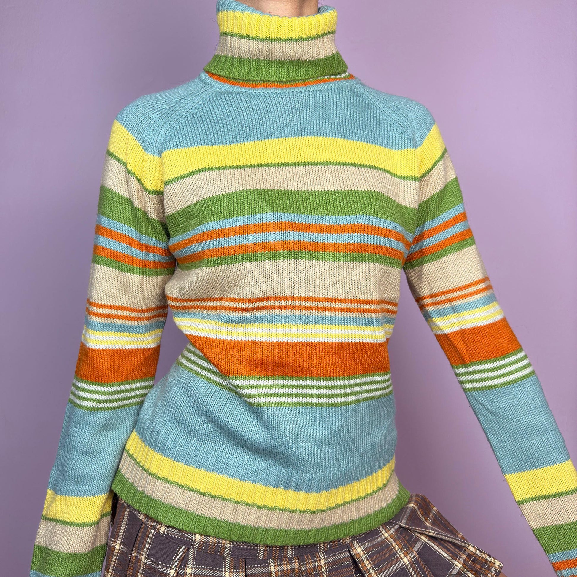 The Y2K Striped Turtleneck Sweater is a vintage 2000s classic featuring a cozy ribbed turtleneck design. Crafted from a knit fabric, it showcases bold multicolor horizontal stripes. adult world shop