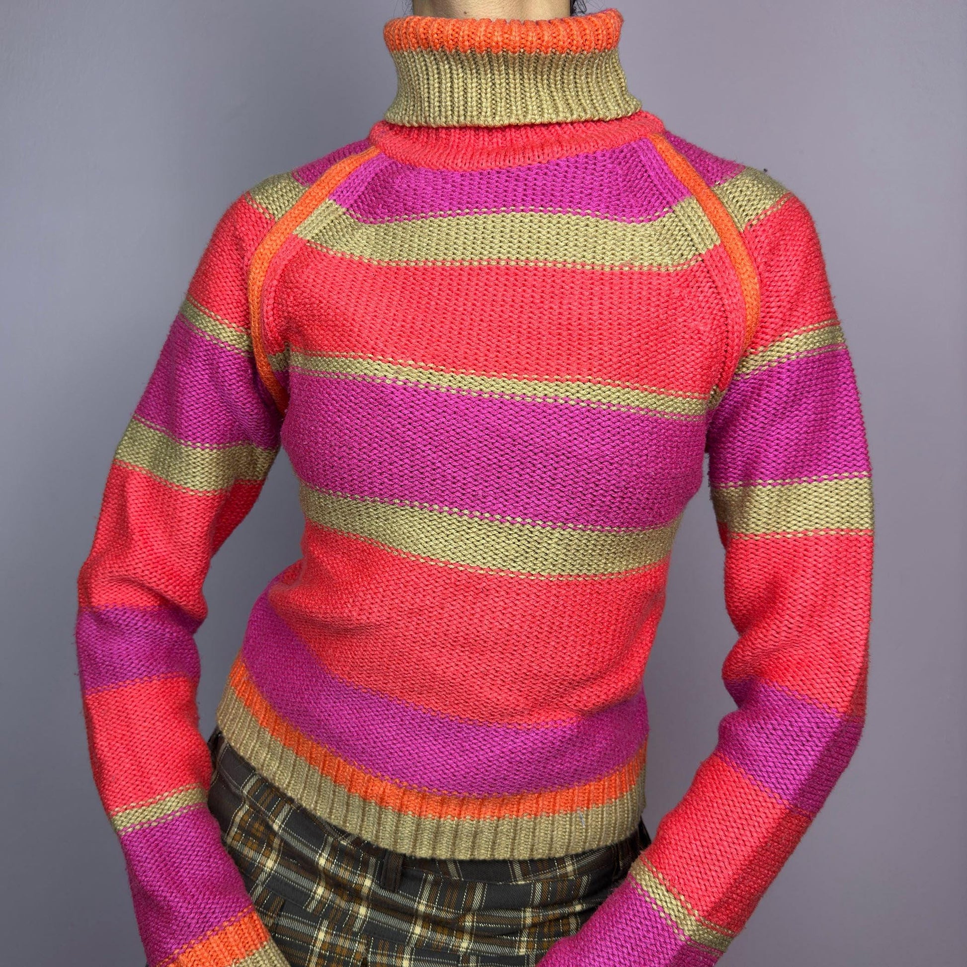 The Y2K Turtleneck Striped Sweater is a vintage 2000s staple featuring a bold striped design in vibrant tones. Crafted from a knit fabric, it has a cozy ribbed turtleneck, cuffs, and hem for a snug fit. adult world shop