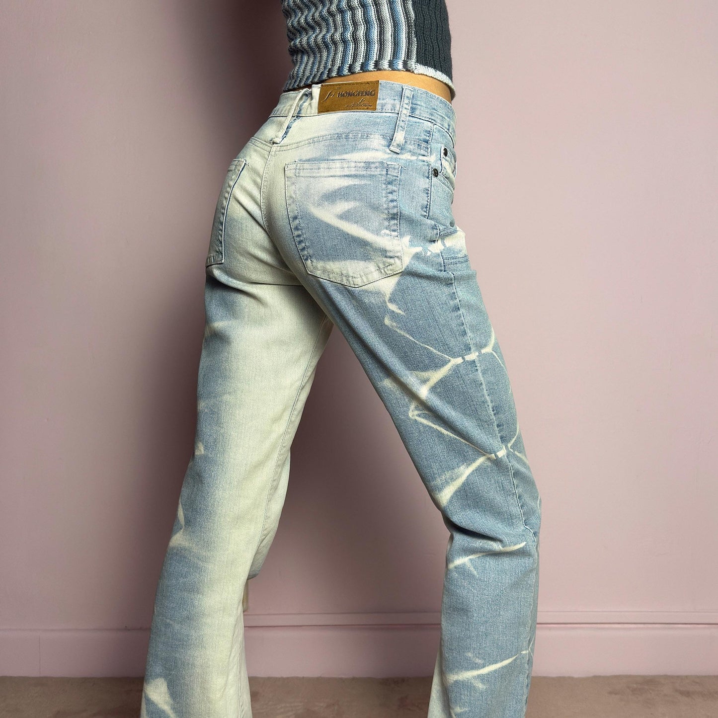 The Y2K Bleached Flare Jeans are a vintage 2000s statement piece featuring a light-wash denim with a bold bleached abstract pattern for a deconstructed, experimental look. Designed with a flattering mid-rise fit, flared legs, button and zipper closure, and pockets, these jeans are a perfect blend of edgy and playful aesthetics. Ideal for standout casual outfits. adult world shop
