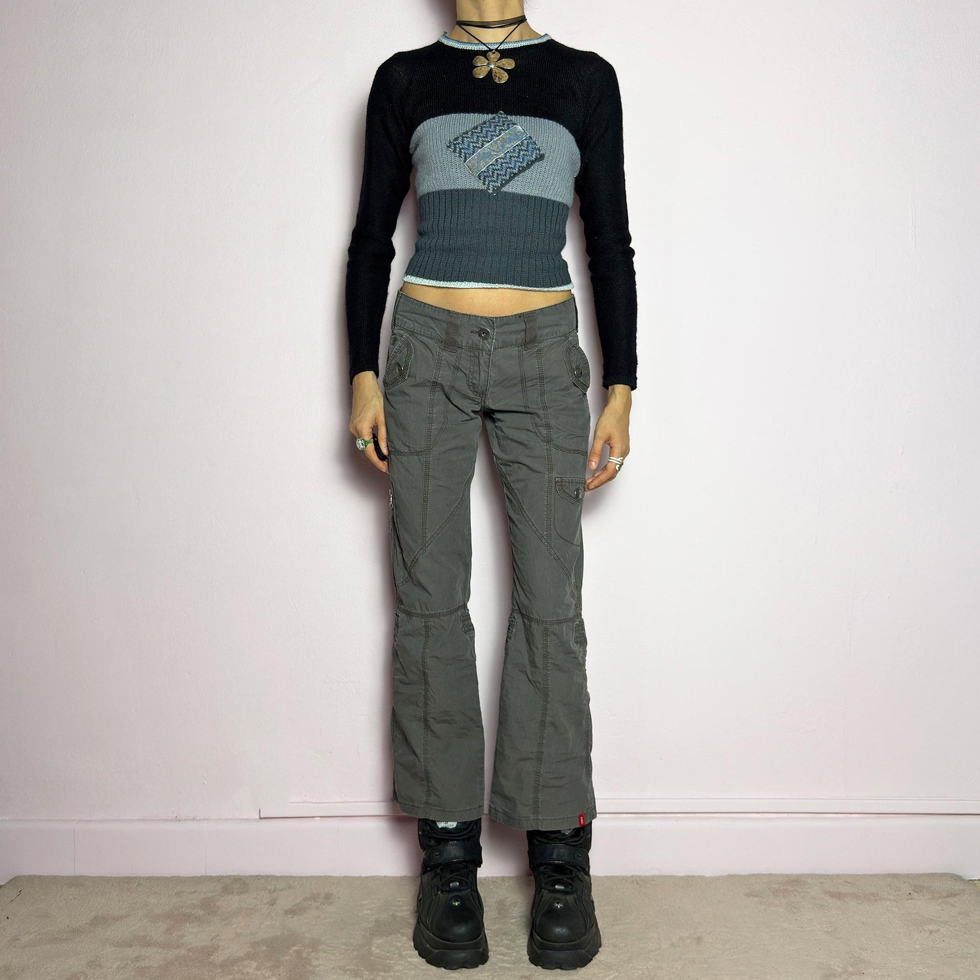 The Y2K Low-Rise Cargo Pants are a vintage 2000s piece featuring a washed gray tone with contrast stitching. Designed with a low-rise fit, button and zipper closure, and multiple cargo-style pockets, these pants have panel detailing and exposed seams that enhance their utilitarian aesthetic. The cropped straight-leg cut adds a modern touch, making them perfect for grunge and streetwear-inspired outfits. adult world shop
