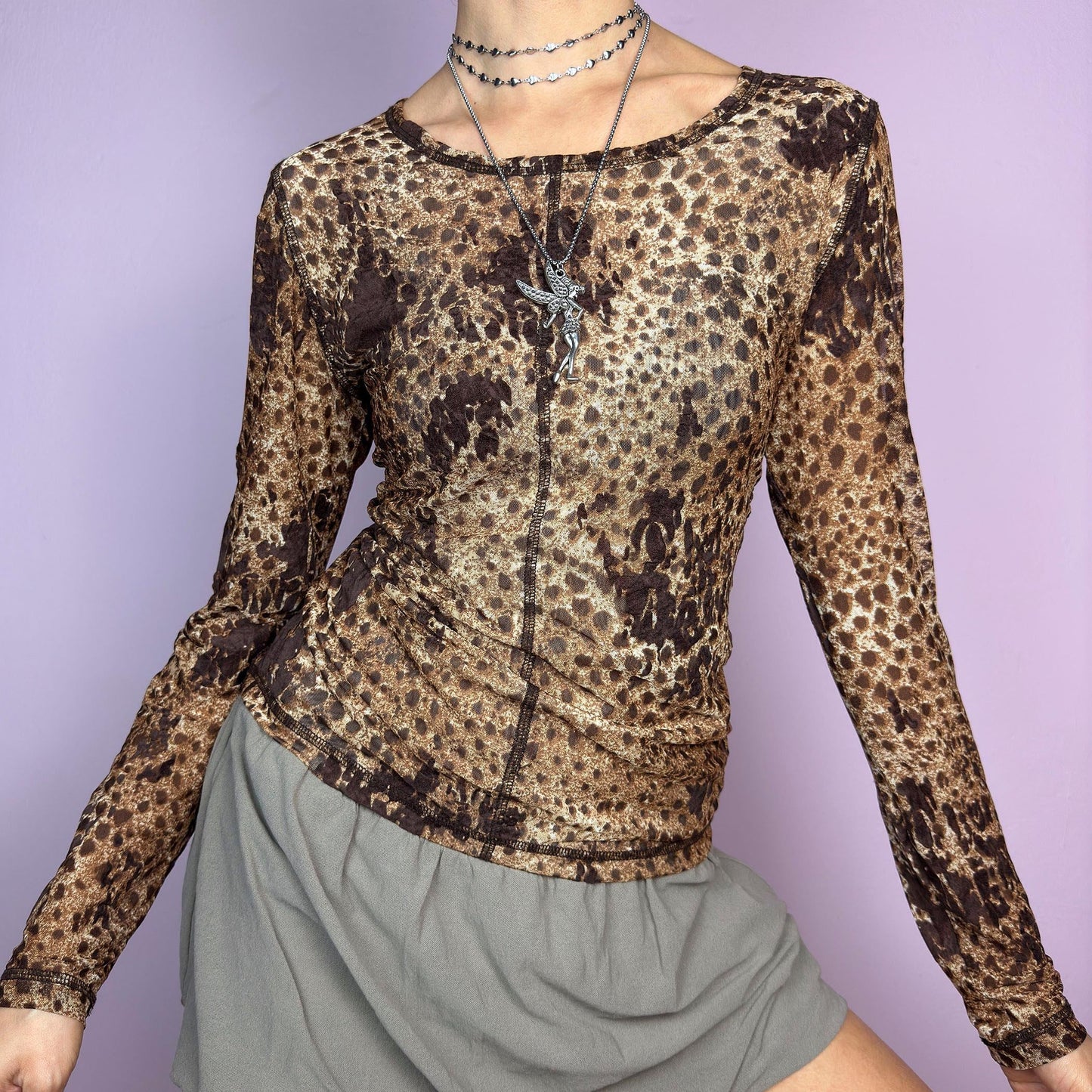 The Y2K Animal Print Mesh Top is a vintage 2000s sheer long-sleeve top featuring a bold cheetah-inspired print in earthy brown tones. Designed with visible contrast stitching, and a soft stretch mesh fabric, this piece is perfect for casual or night-out looks. adult world shop