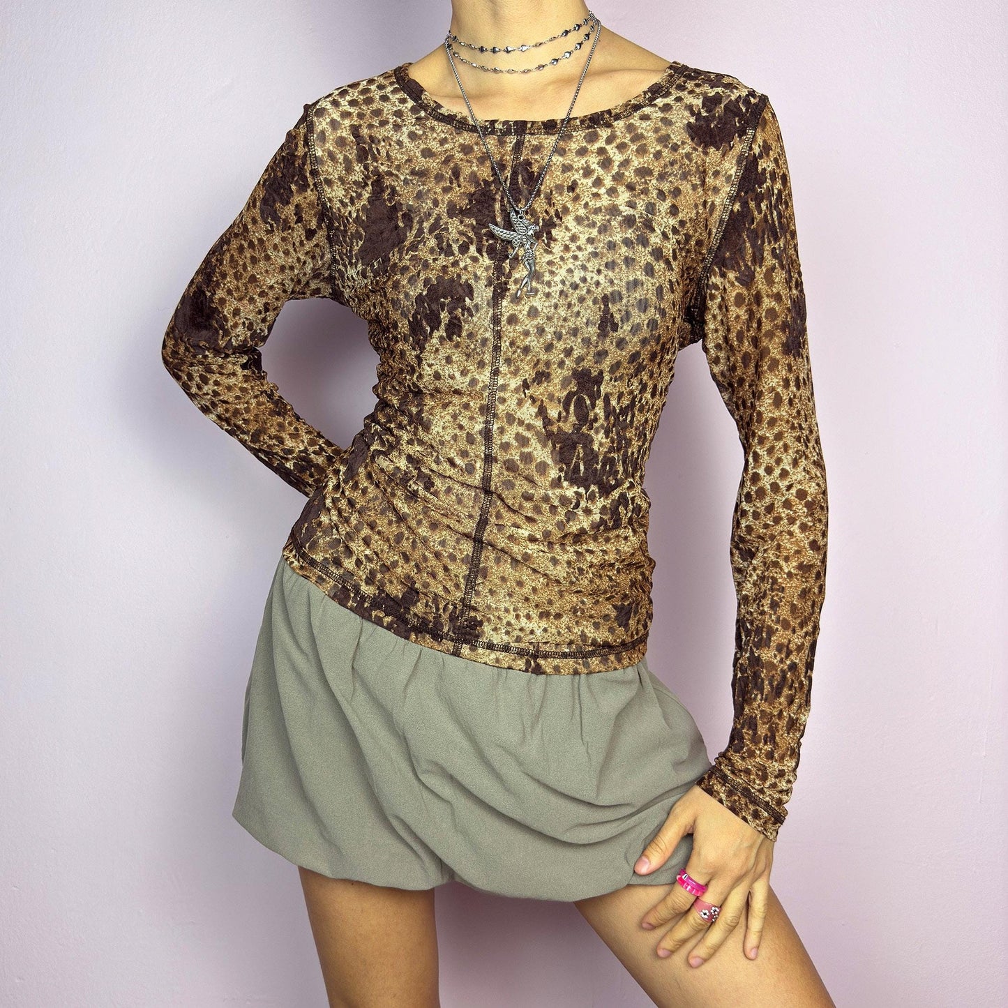 The Y2K Animal Print Mesh Top is a vintage 2000s sheer long-sleeve top featuring a bold cheetah-inspired print in earthy brown tones. Designed with visible contrast stitching, and a soft stretch mesh fabric, this piece is perfect for casual or night-out looks. adult world shop