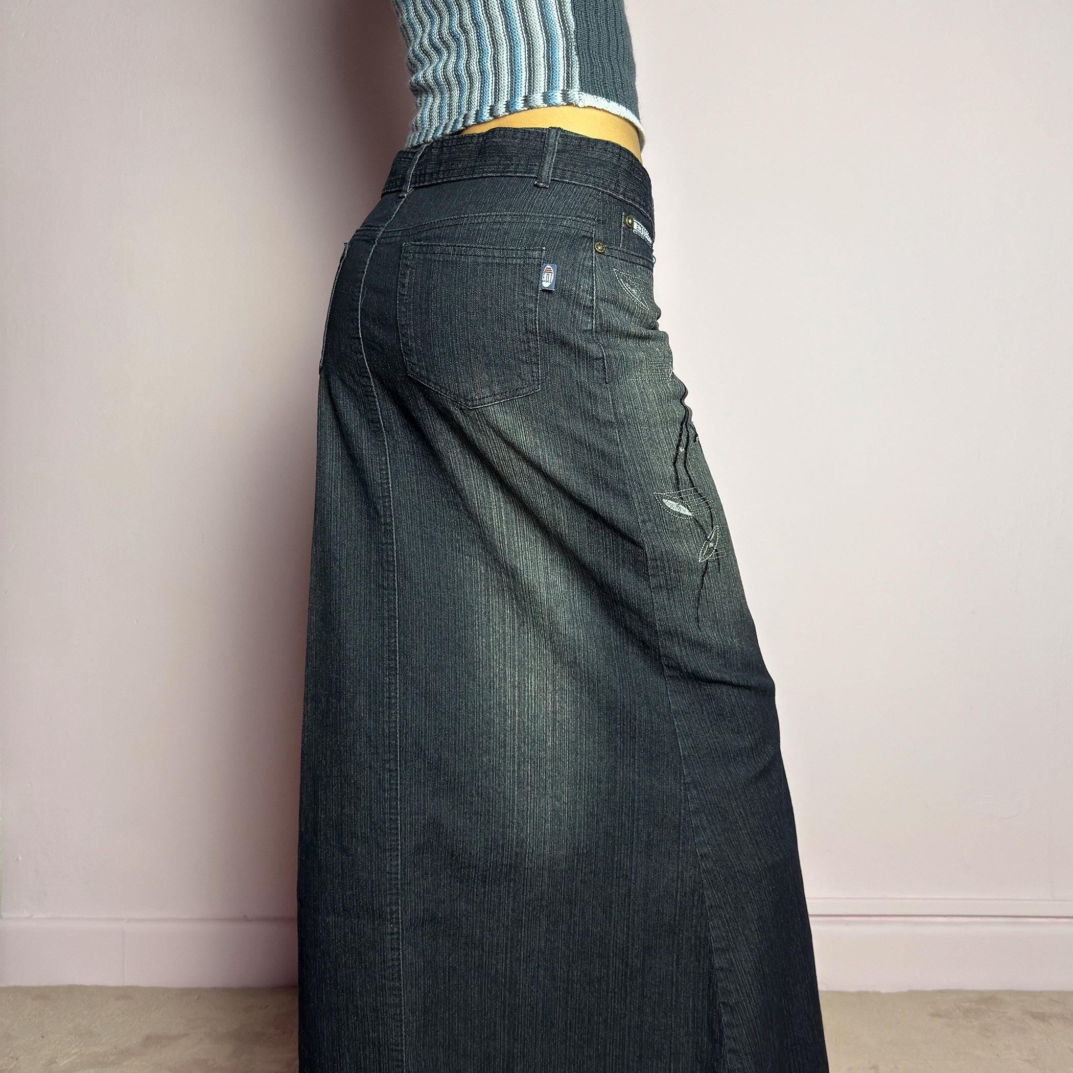 The Y2K Black Denim Maxi Skirt is a vintage 2000s piece featuring a sleek dark wash, rhinestone embellishments, and contrast stitching. Designed with a mid-rise fit and a stretchy denim fabric, it offers a structured silhouette that flares at the bottom. The skirt is finished with a button and zipper closure, pockets, and a removable belt for a customizable look. Perfect for casual streetwear outfits or an elegant night out. adult world shop