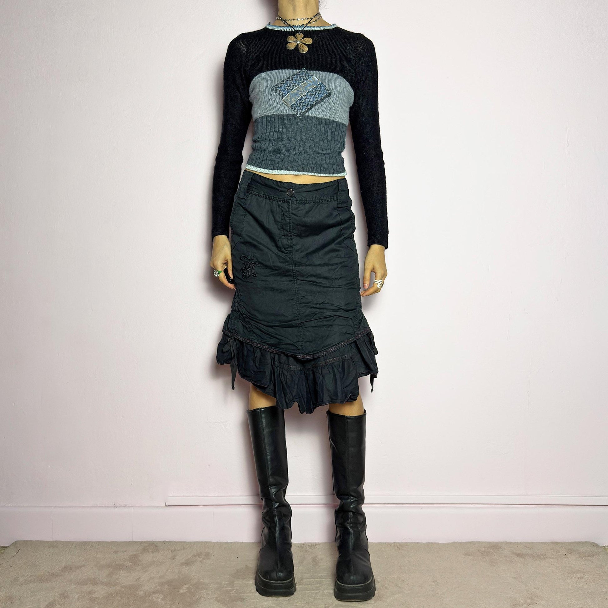 The Y2K Black Layered Skirt by Marithé François Girbaud is a vintage 2000s statement piece featuring a structured design with ruched details and ruffled layers for added texture and movement. Designed with a mid-rise fit, button and zipper closure, embroidered side detail, and an asymmetrical hem, this skirt blends edgy streetwear vibes with a playful, gothic aesthetic. Perfect for casual grunge and alternative looks. adult world shop