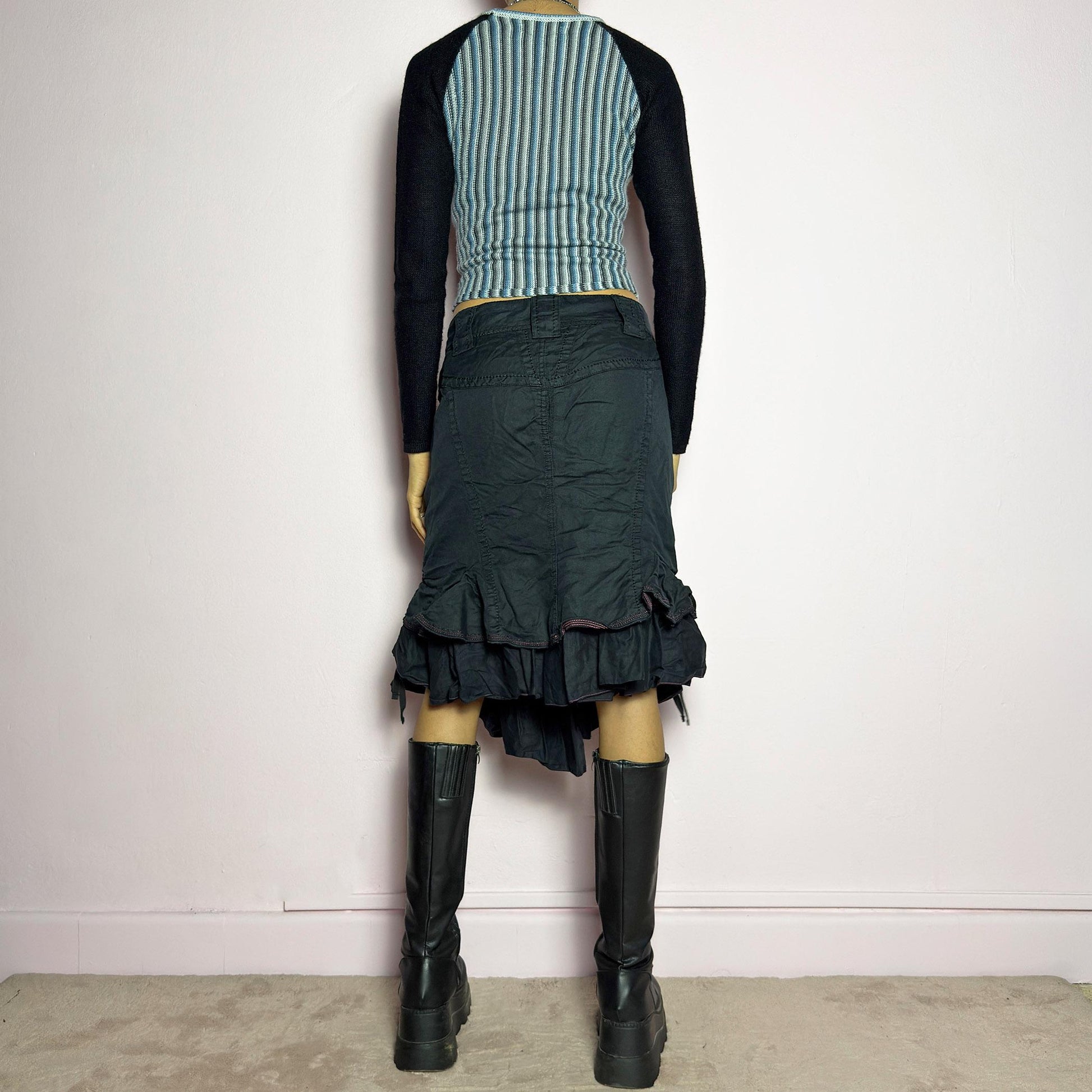 The Y2K Black Layered Skirt by Marithé François Girbaud is a vintage 2000s statement piece featuring a structured design with ruched details and ruffled layers for added texture and movement. Designed with a mid-rise fit, button and zipper closure, embroidered side detail, and an asymmetrical hem, this skirt blends edgy streetwear vibes with a playful, gothic aesthetic. Perfect for casual grunge and alternative looks. adult world shop