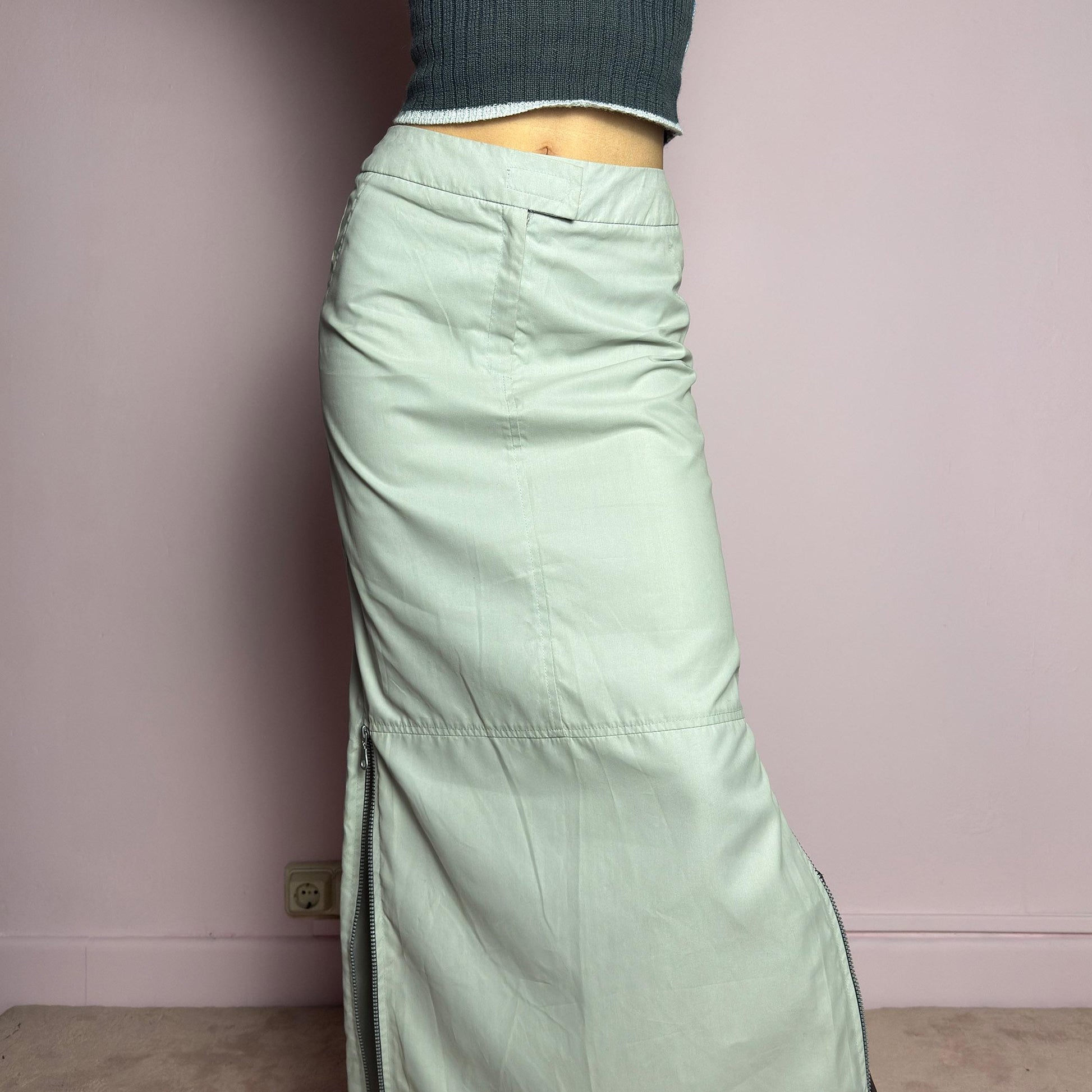 The Y2K Light Gray Maxi Skirt is a vintage 2000s piece with a sleek, futuristic aesthetic. Featuring a structured fit, and a high-rise waist, this skirt is designed for a modern, minimal look. Made from lightweight fabric, it offers a flattering silhouette with dual side zipper slits for adjustable styling. Perfect for casual, streetwear, or cyber-inspired avant-garde outfits. adult world shop